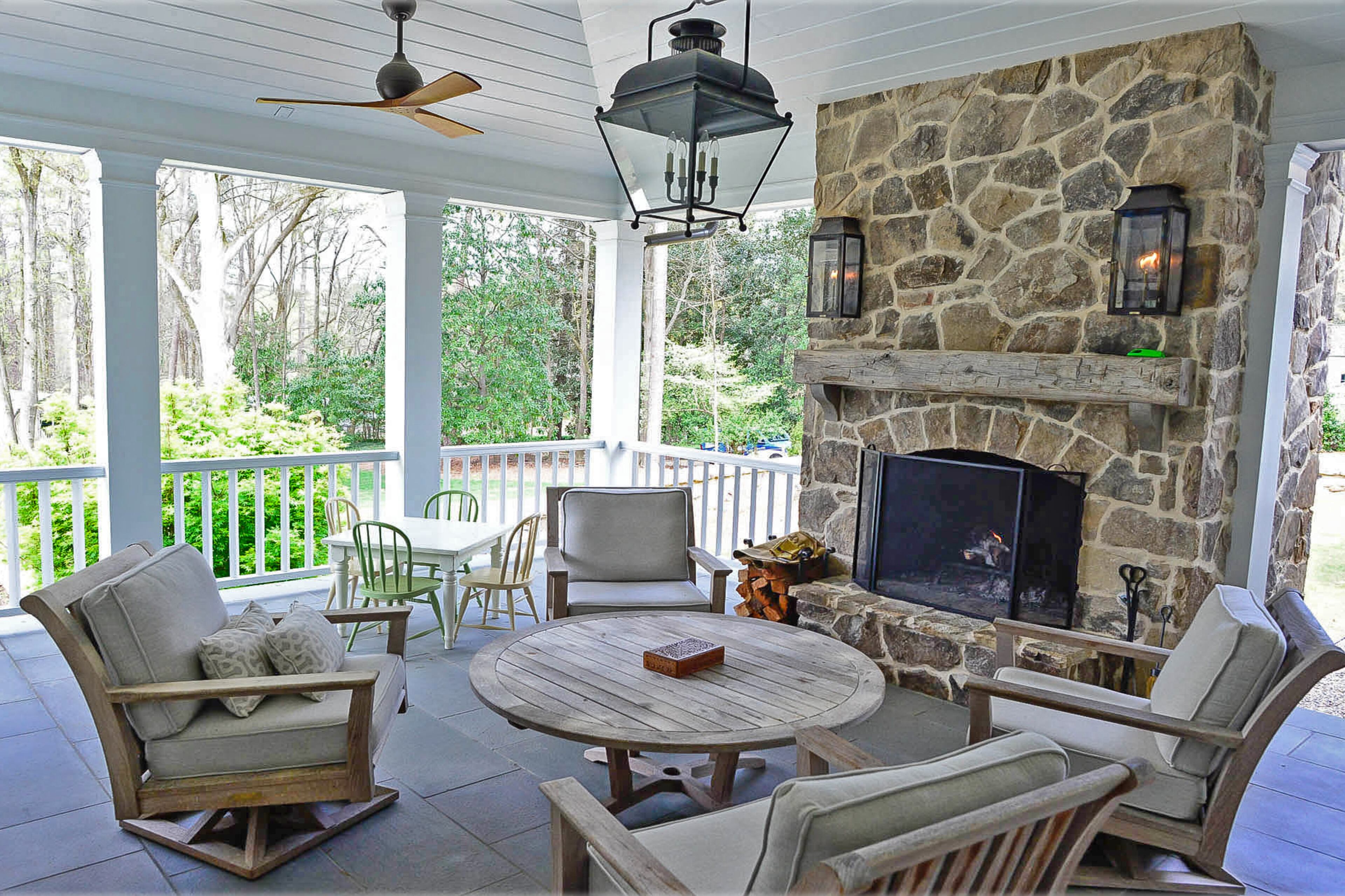 The covered back porch, with its vaulted ceiling, uses the same Tennessee fieldstone that is seen on the front of the home and its chimneys. The Bevolo lanterns are from Circa Lighting.