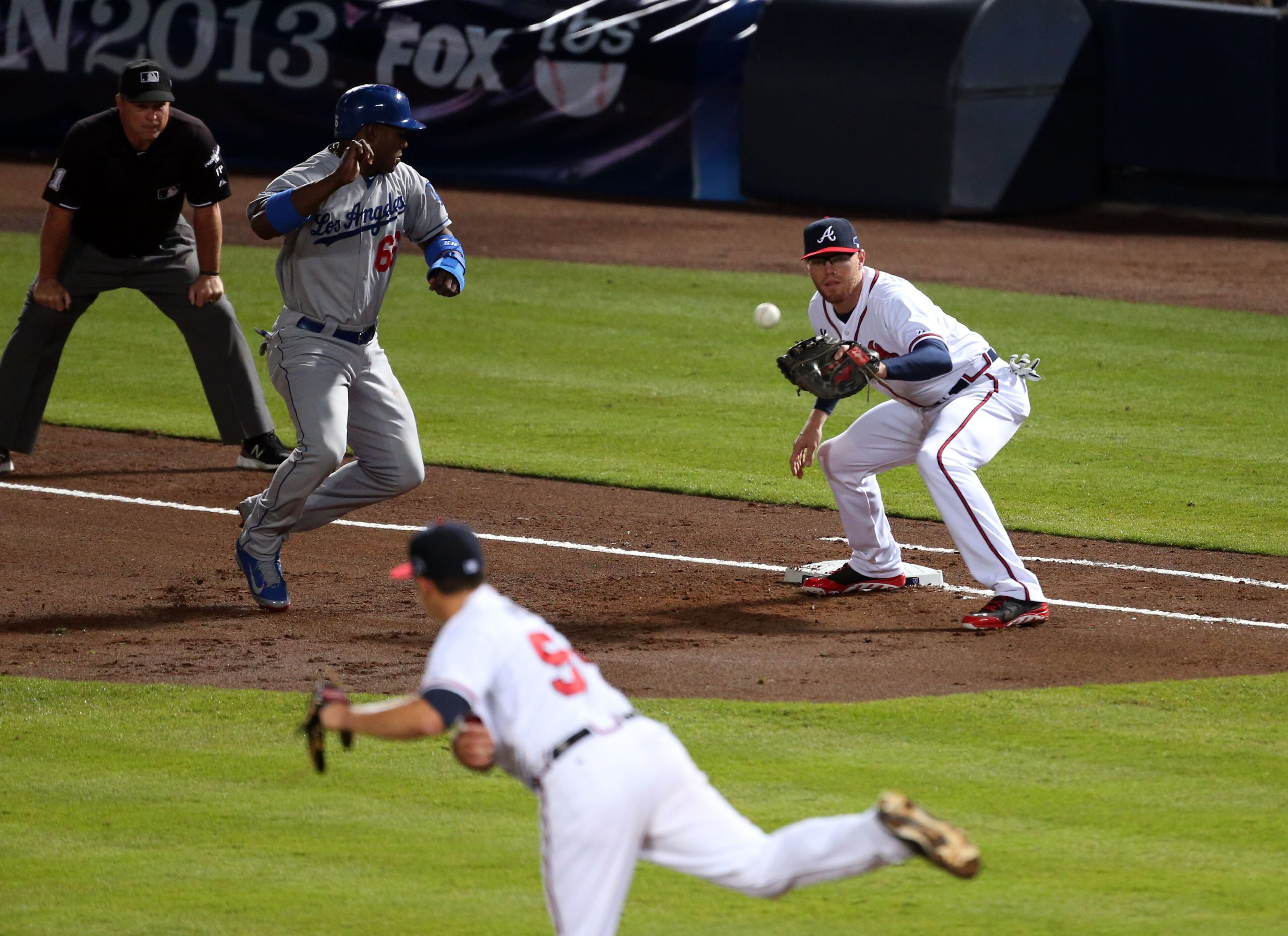 Los Angeles Dodgers right fielder Yasiel Puig (66) gets back to first safe on the pickoff throw from Atlanta Braves starting pitcher Kris Medlen (54) to Atlanta Braves first baseman Freddie Freeman (5) in the 2ned inning during the first game of the National League Division series between the Los Angeles Dodgers and Atlanta Braves at Turner Field, Thursday, October 3, 2013.