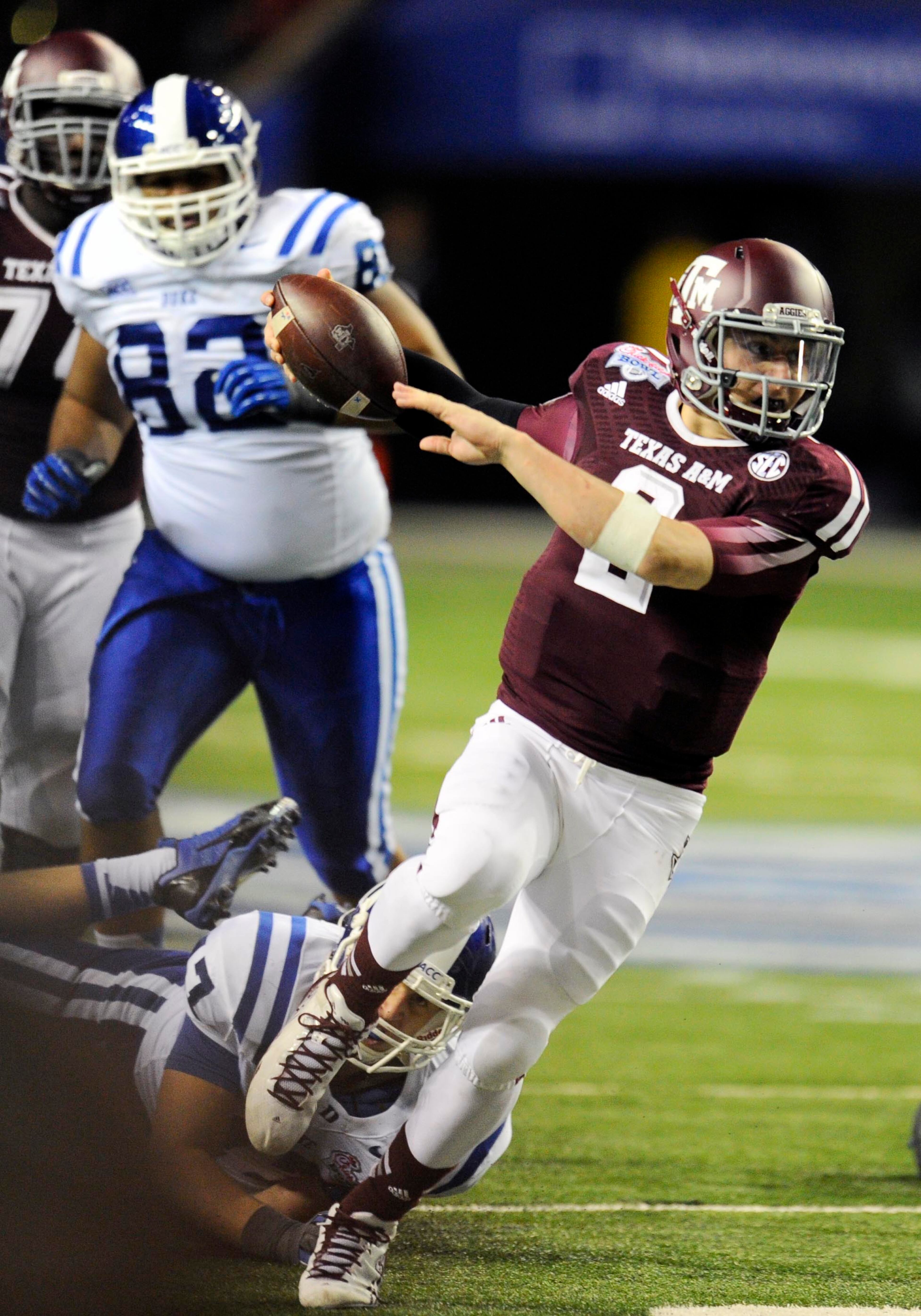 Texas A&M Aggies quarterback Johnny Manziel (2) carries the ball past Duke Blue Devils linebacker David Helton (47) and Sydney Sarmiento (82) during the third quarter in the 2013 Chick-fil-a Bowl at the Georgia Dome.