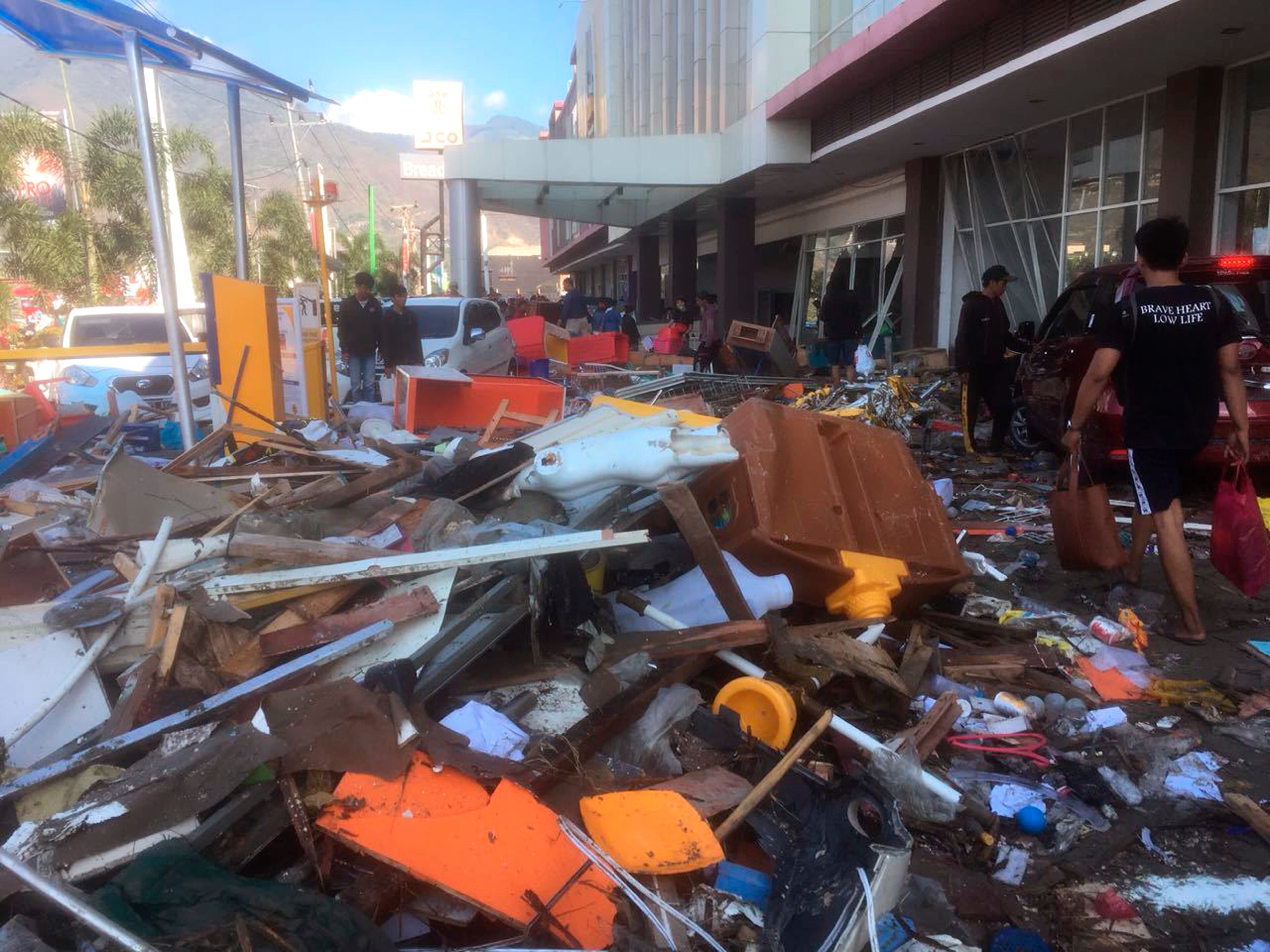 People survey the damage following earthquakes and tsunami in Palu, Central Sulawesi, Indonesia, Sunday, Sept. 30, 2018. A tsunami swept away buildings and killed large number of people on the Indonesian island of Sulawesi, dumping victims caught in its relentless path across a devastated landscape that rescuers were struggling to reach Saturday, hindered by damaged roads and broken communications. (AP Photo/Tatan Syuflana)