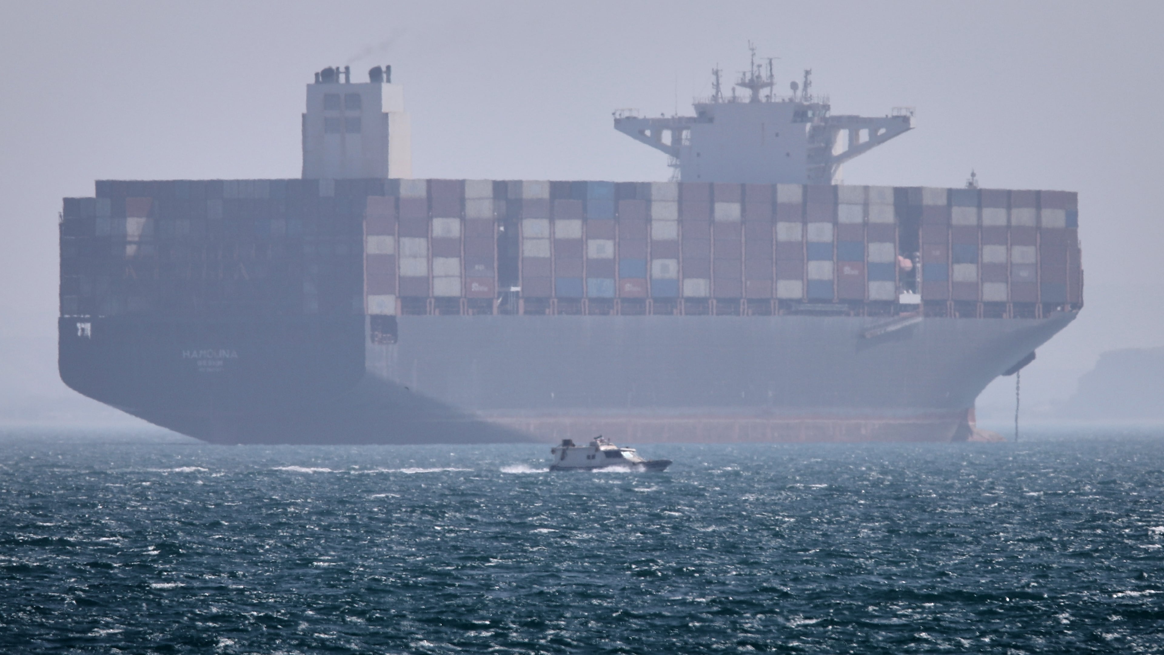 A container ship sits at anchor as a small motorboat passes in the foreground in the Strait of Hormuz off Bandar Abbas, Iran, Saturday, May 2, 2026. (Amirhosein Khorgooi/ISNA via AP)