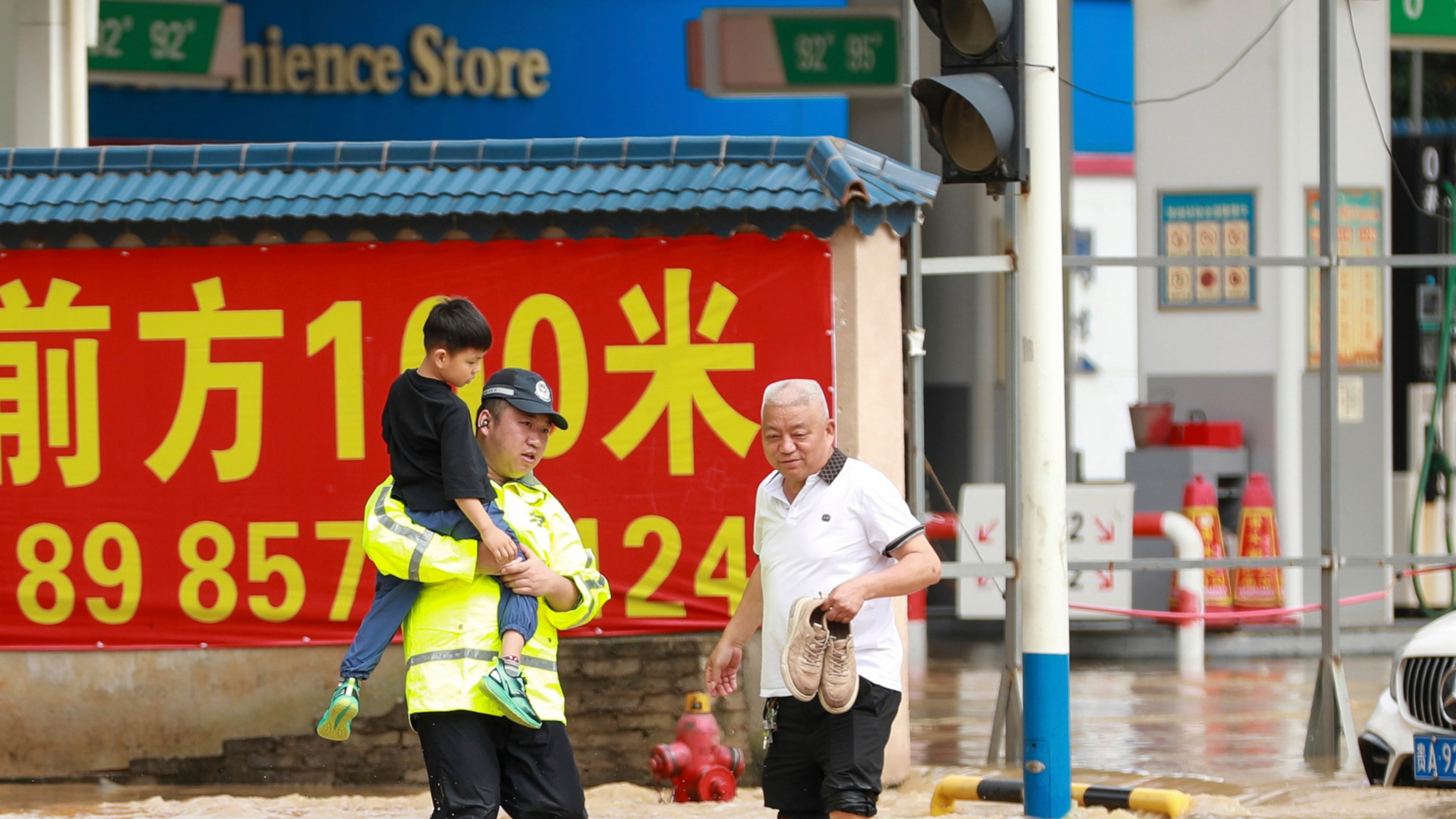 In this photo released by Xinhua News Agency, a police officer holds a boy as he wades through a flooded street in Duyun city, southwestern China's Guizhou Province on Tuesday, May 19, 2026. (Xiao Wei/Xinhua via AP)