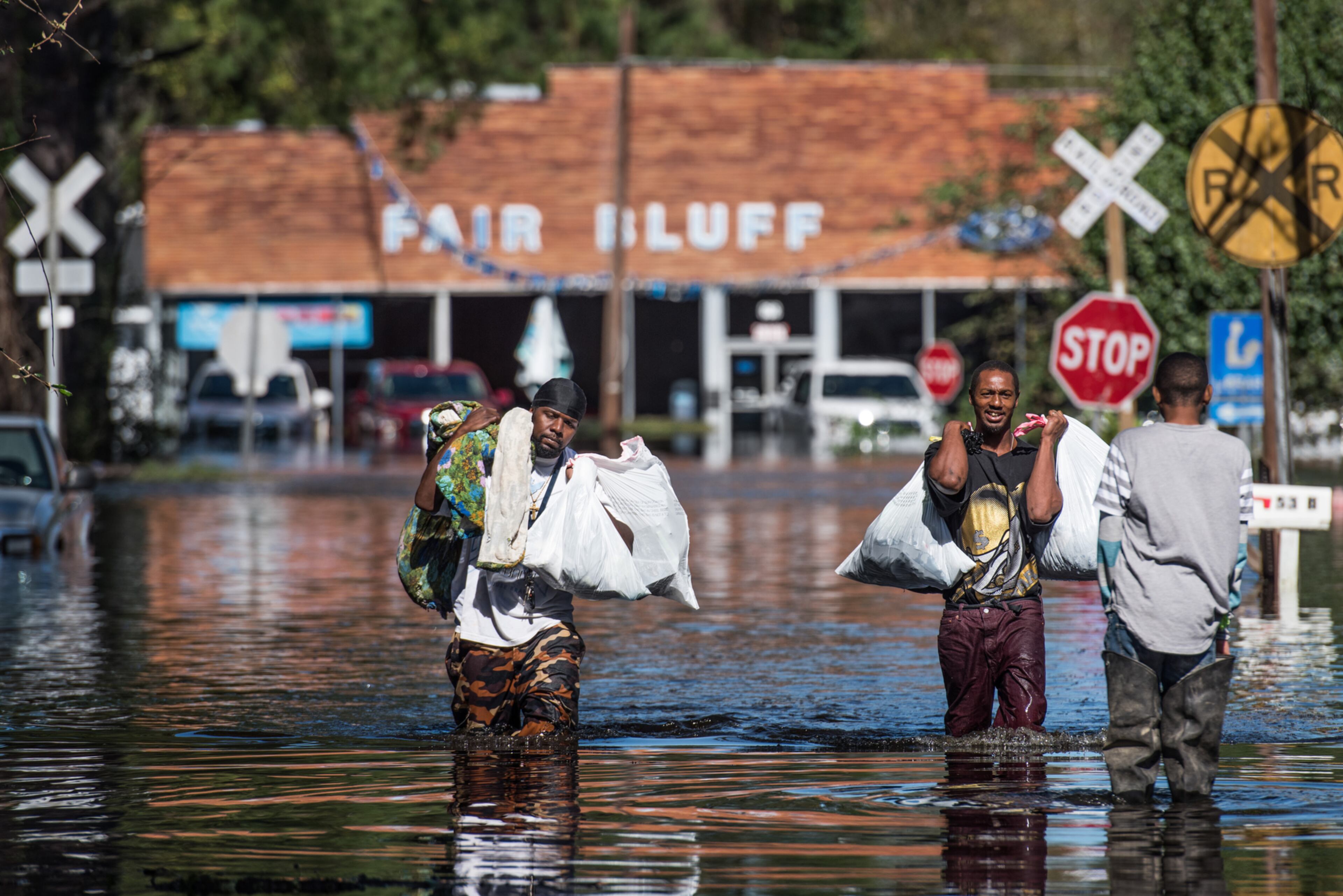 FAIR BLUFF, NC - OCTOBER 11: Vance Barden, left, and Wayne Edwards carry personal items through a flooded street caused by remnants of Hurricane Matthew on October 11, 2016 in Fair Bluff, North Carolina. Thousands of homes have been damaged in North Carolina as a result of the storm and many are still under threat of flooding. (Photo by Sean Rayford/Getty Images)