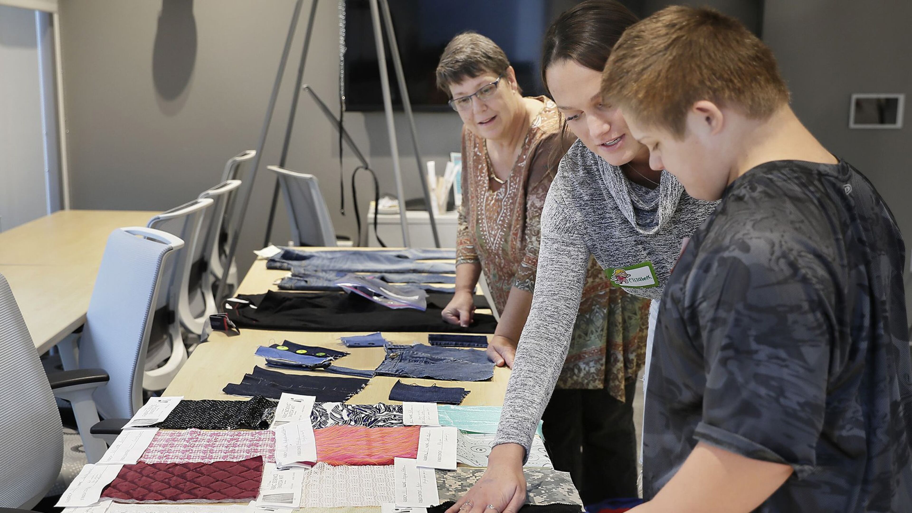 As Janet Littleton of Laurel, Del. watches, University of Delaware senior Elizabeth deBruin shows fabric swatches to Littleton’s grandson, 11-year-old Jayden Niblett of Seaford, Del. (Elizabeth Robertson/The Philadelphia Inquirer/TNS)