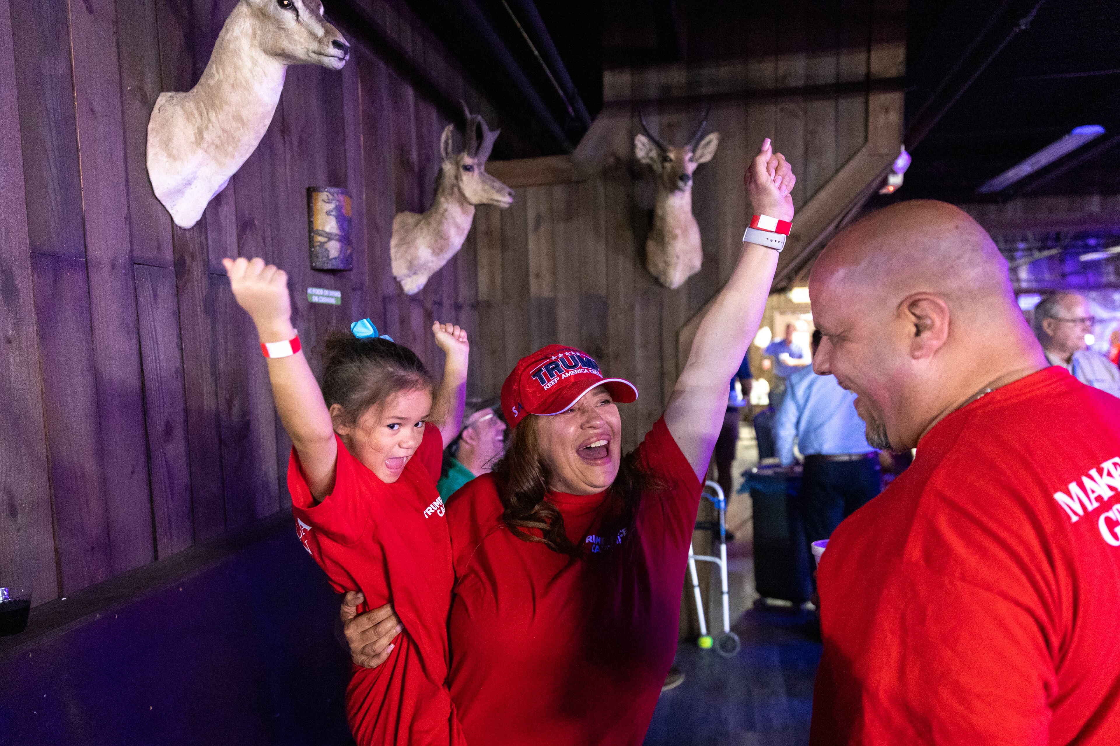 Tiana Robinson (center) and her niece Lulu, 5, cheer at a Republican presidential debate watch party at gun store and indoor shooting range Adventure Outdoor in Smyrna on Tuesday, September 10, 2024. Candidates Vice President Kamala Harris and former President Donald Trump are debating in Philadelphia. (Arvin Temkar / AJC)