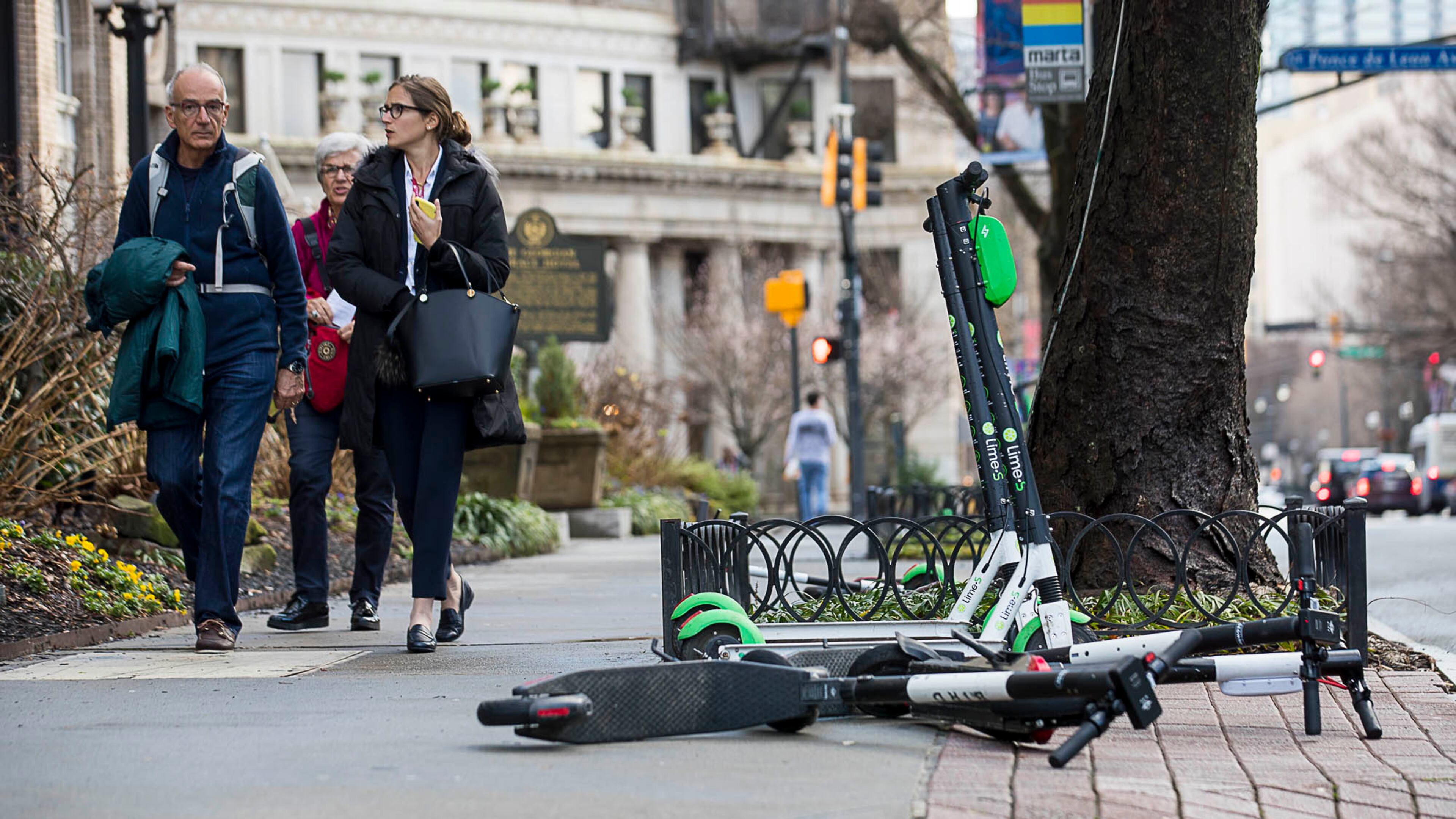 01/04/2019 -- Atlanta, Georgia -- Pedestrians walk past Lime and Bird scooters that are parked on the sidewalk of Peachtree Street in Atlanta's Midtown community, Friday, January 4, 2019. (ALYSSA POINTER/ALYSSA.POINTER@AJC.COM)