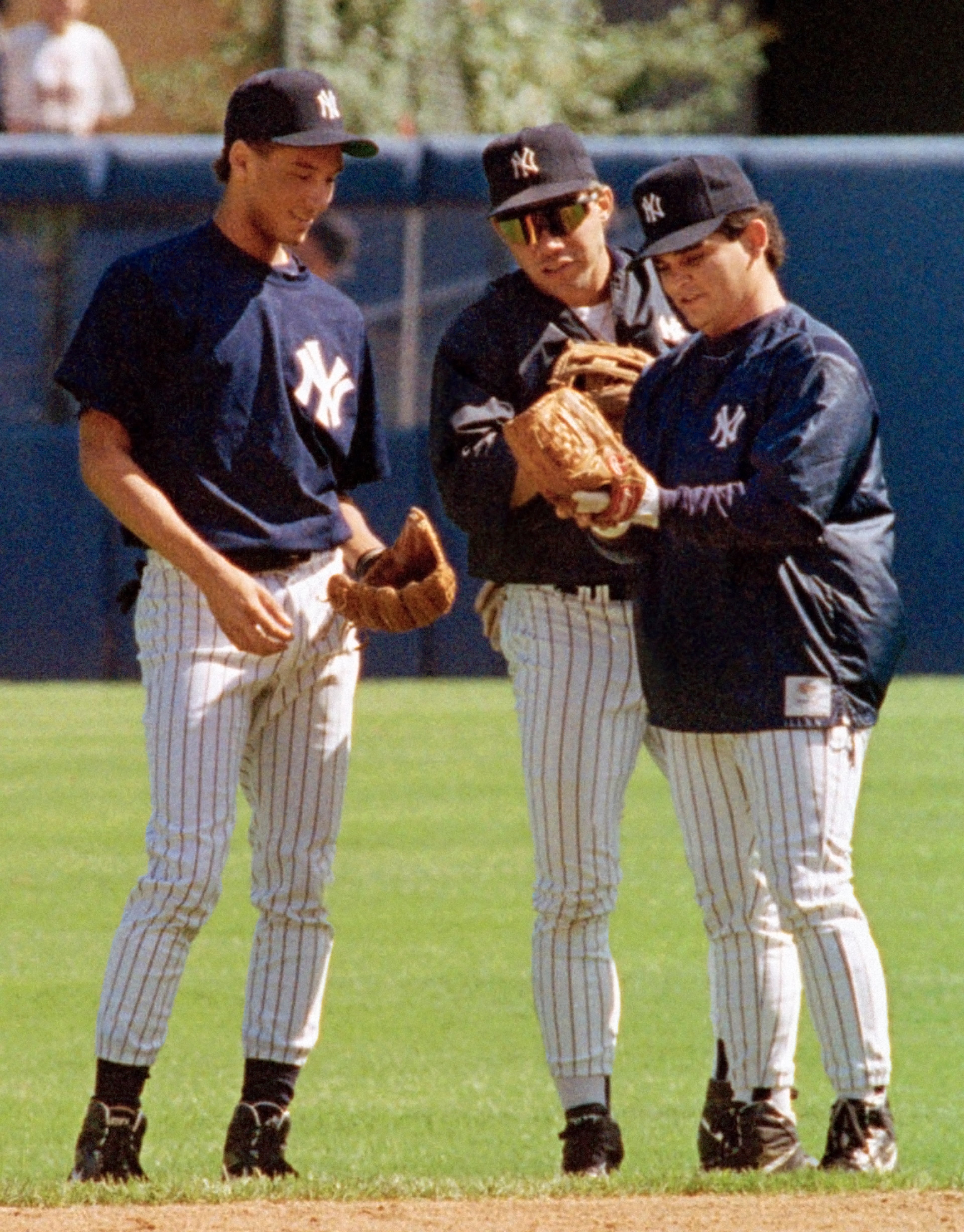 FILE - In this Sept. 12, 1992, file photo ,Derek Jeter, left, New York Yankees to prospect Derek Jeter, left, compares gloves with Jim Leyritz, center, and Mike Gallego before a baseball game against the Kansas City Royals at Yankee Stadium in New York. A five-time World Series champion and sixth on the career hits list, Jeter, now 40, is set to retire after this season after spending two decades as the shortstop for the Yankees. (AP Photo/Richard Harbus, File)
