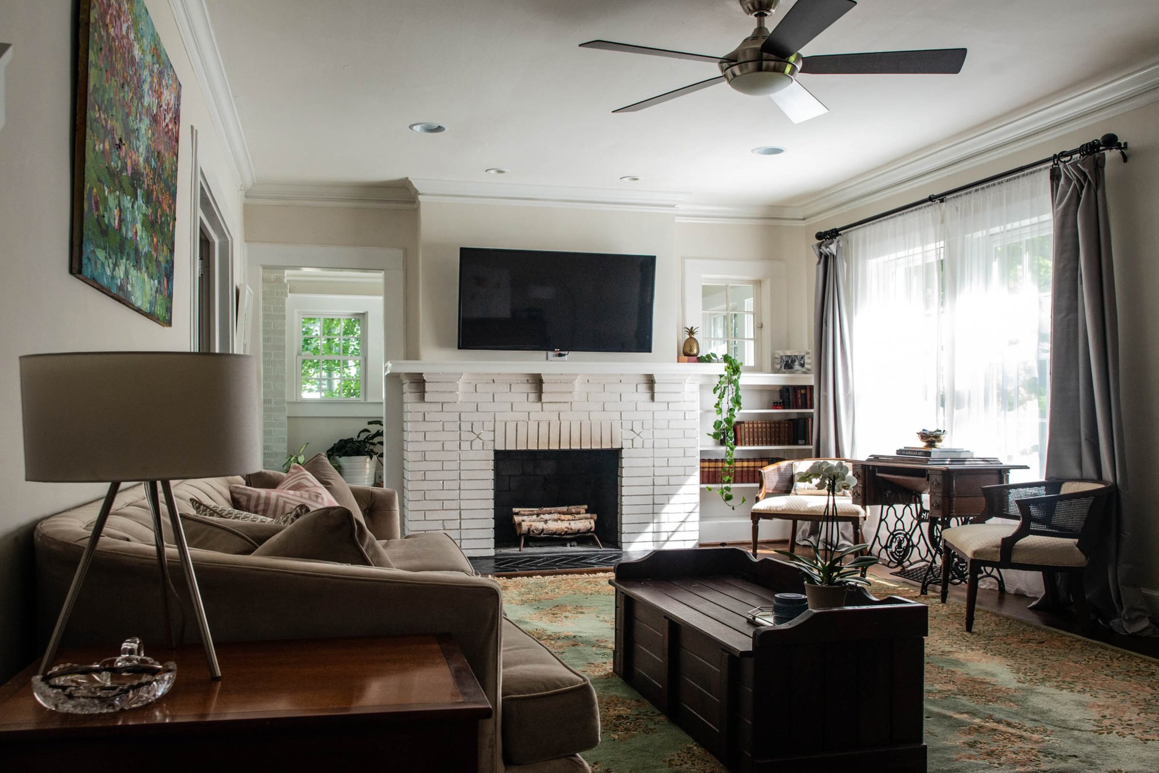 In the living room, the original fireplace and other items, such as the antique oriental rug, a Singer sewing machine table and toy box-turned-coffee table, reference years past. (Christopher Oquendo)