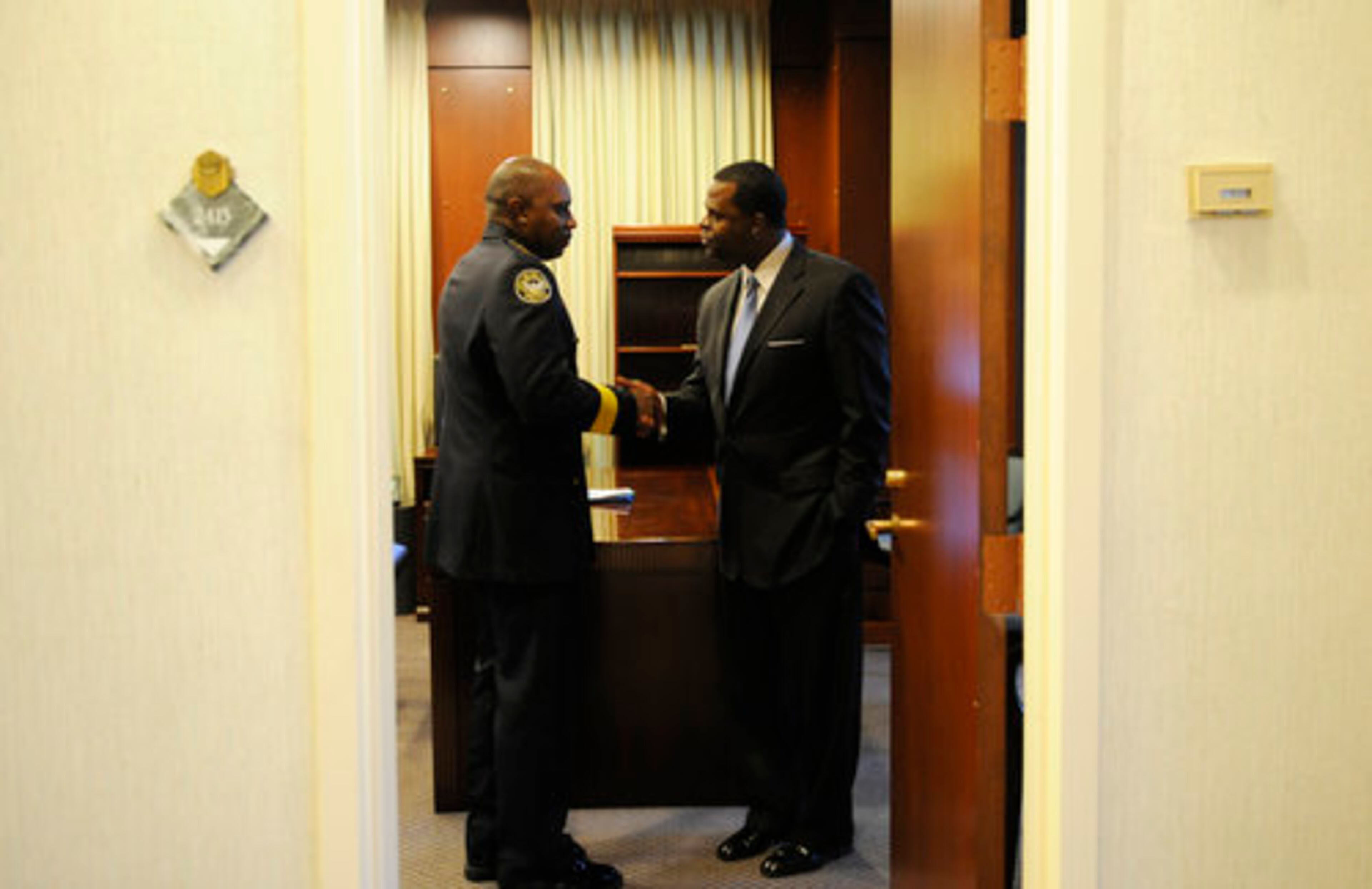From left, Acting Police Chief for the Atlanta Police Department David Turner shakes hands with Mayor Kasim Reed inside his office.