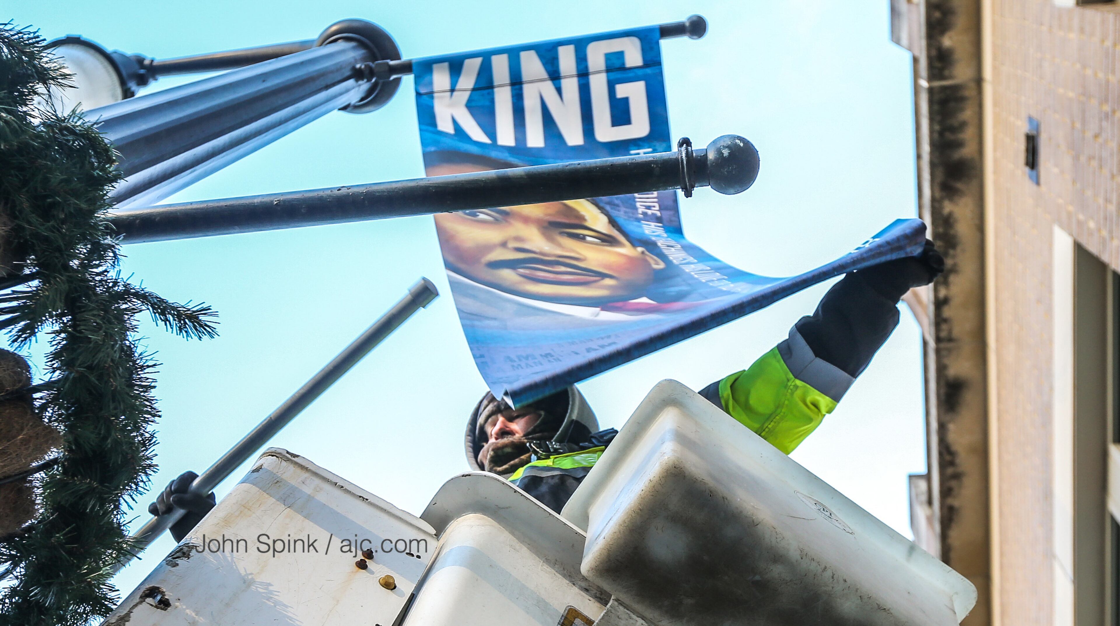 Wright Brown Electric Company’s Keith Bentley tried to stay warm Wednesday morning as he removed MLK banners on Auburn Avenue. JOHN SPINK / JSPINK@AJC.COM