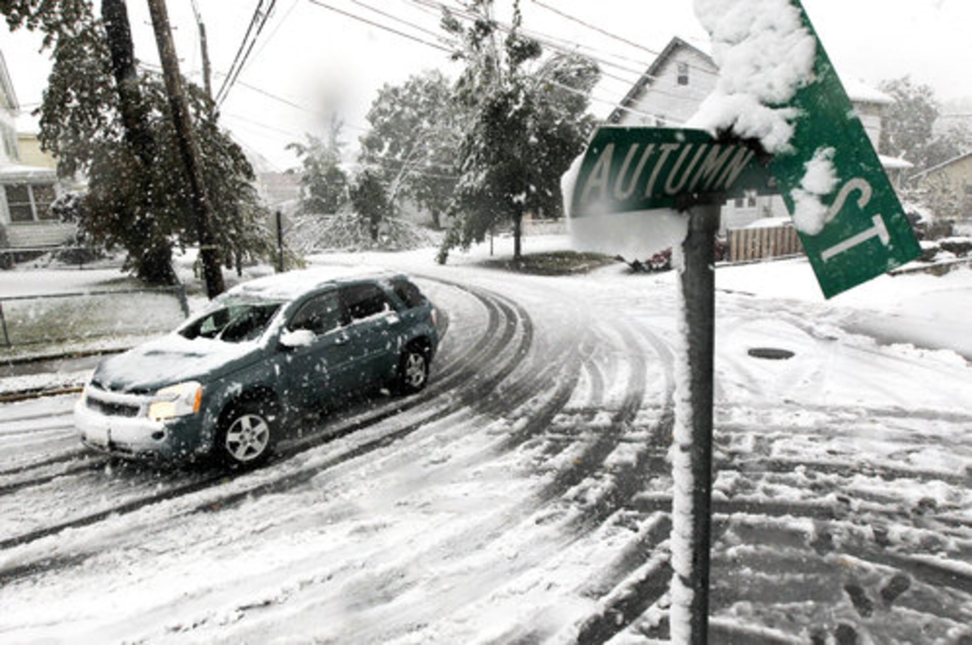 A vehicle makes its way at the snow-covered intersection of Autumn and Grove Streets in Lodi, N.J., following a rare October snowstorm that hit the region.