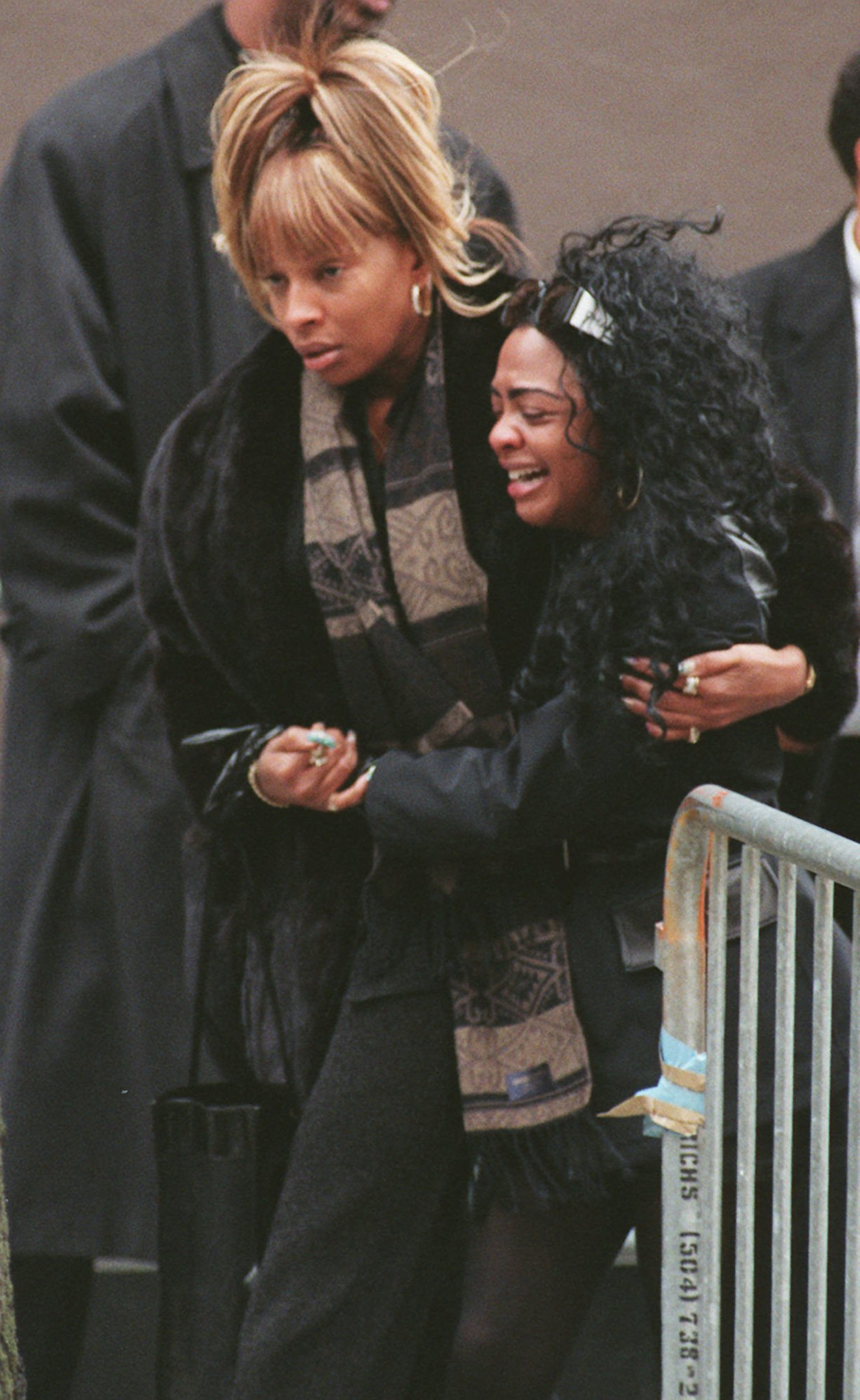 Lil' Kim, right, is escorted by Mary J. Blige following the funeral for rapper Notorious B.I.G at the Frank E. Campbell Funeral Home in New York on March 18, 1997.