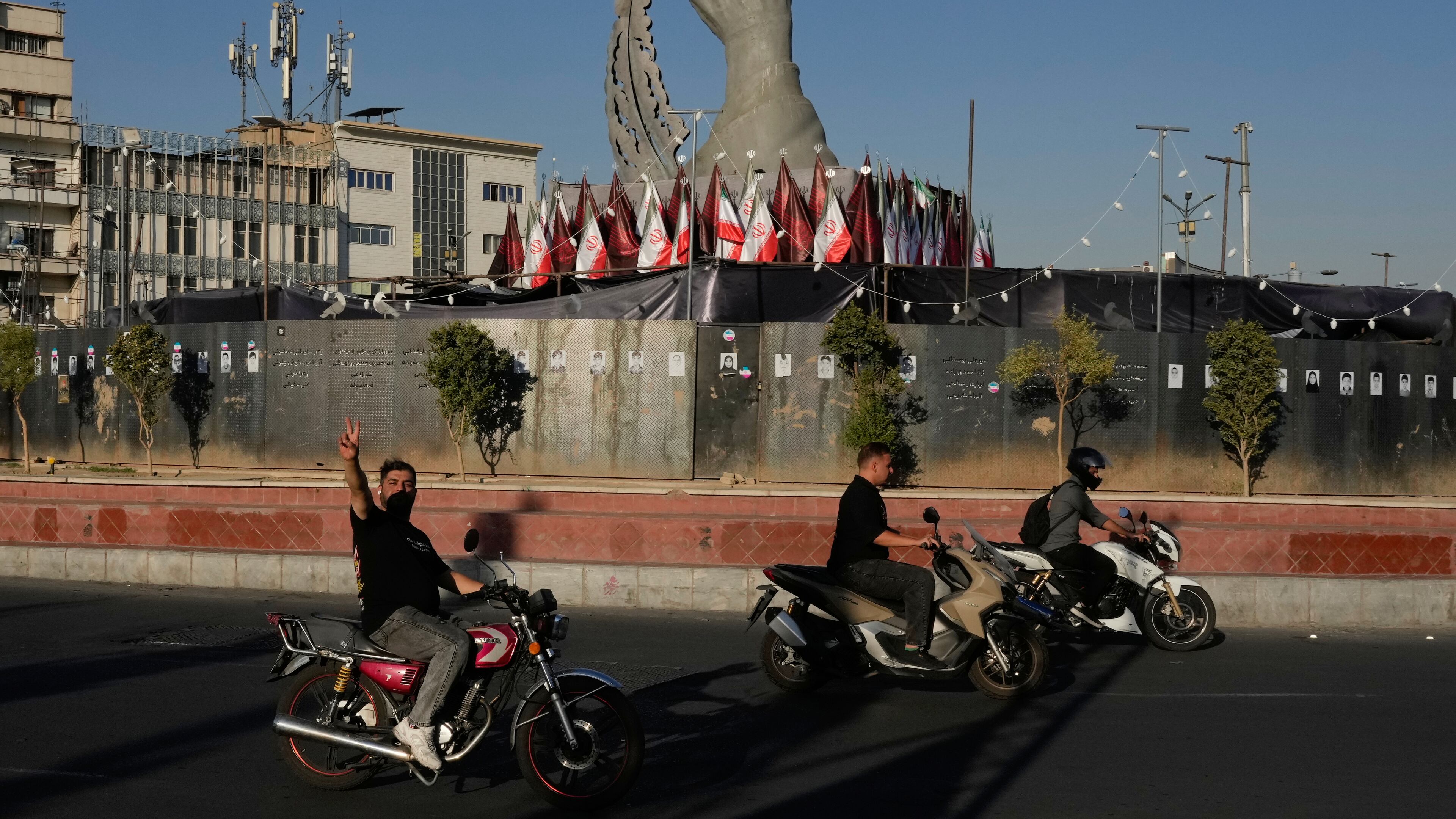 A man reacts to the camera while driving past a monument depicting the clenched fist of the late Iranian Supreme Leader Ayatollah Ali Khamenei, who was killed in the U.S. and Israel strike on Feb. 28, and a missile at the Islamic Revolution square in downtown Tehran, Iran, Tuesday, Sept. 15, 2026. (AP Photo/Vahid Salemi)