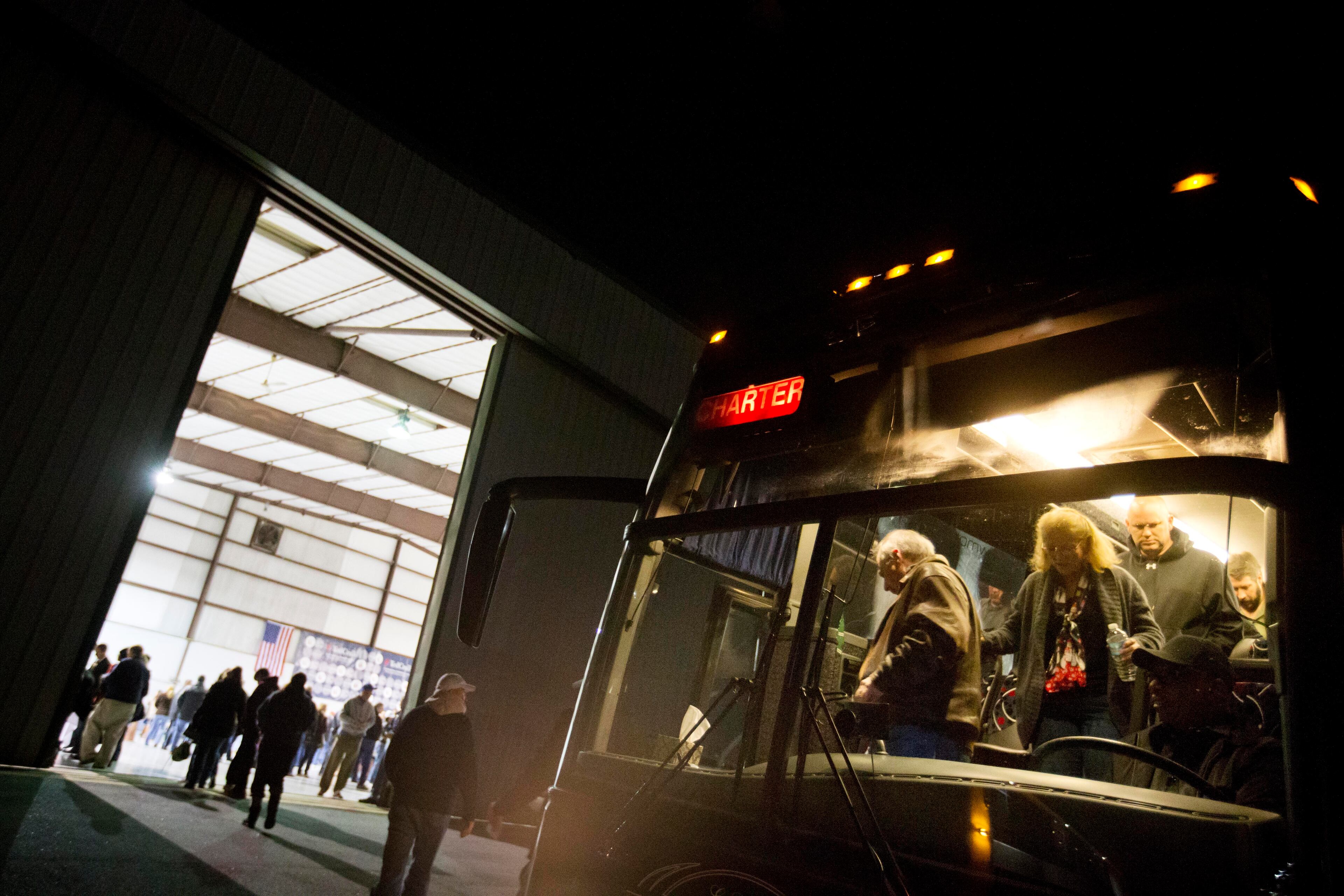 People get off a bus as they arrive for a campaign event at an airport hanger for Republican presidential candidate, Sen. Ted Cruz, R-Texas, Friday, Dec. 18, 2015, in Kennesaw, Ga. (AP Photo/David Goldman)