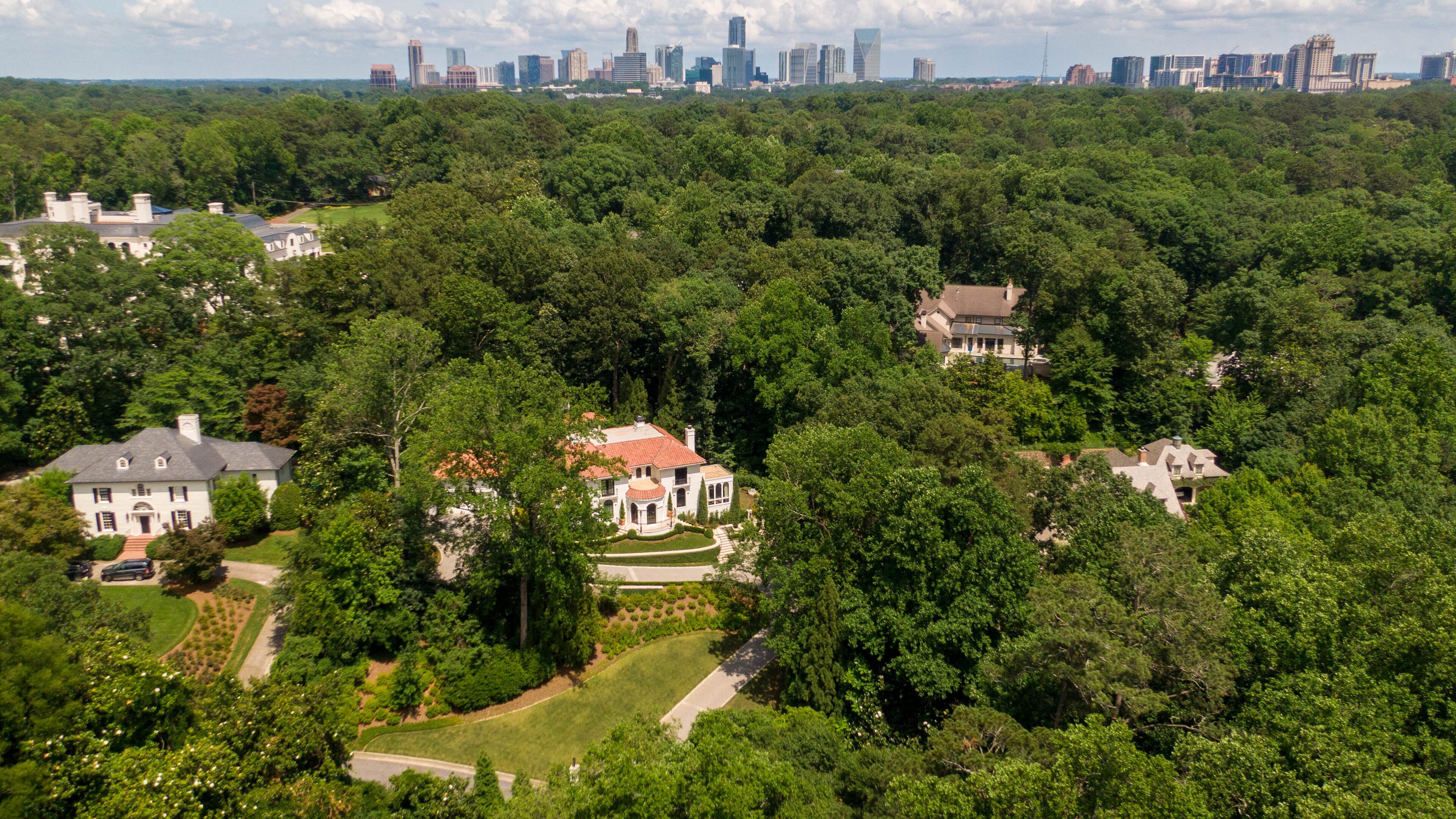 An aerial photo shows some of the homes in Buckhead nestled in trees against part of the Atlanta skyline. Atlanta has adopted a goal of 50% canopy coverage, but the city’s tree cover has been short of that mark for years. (Hyosub Shin/AJC 2021)