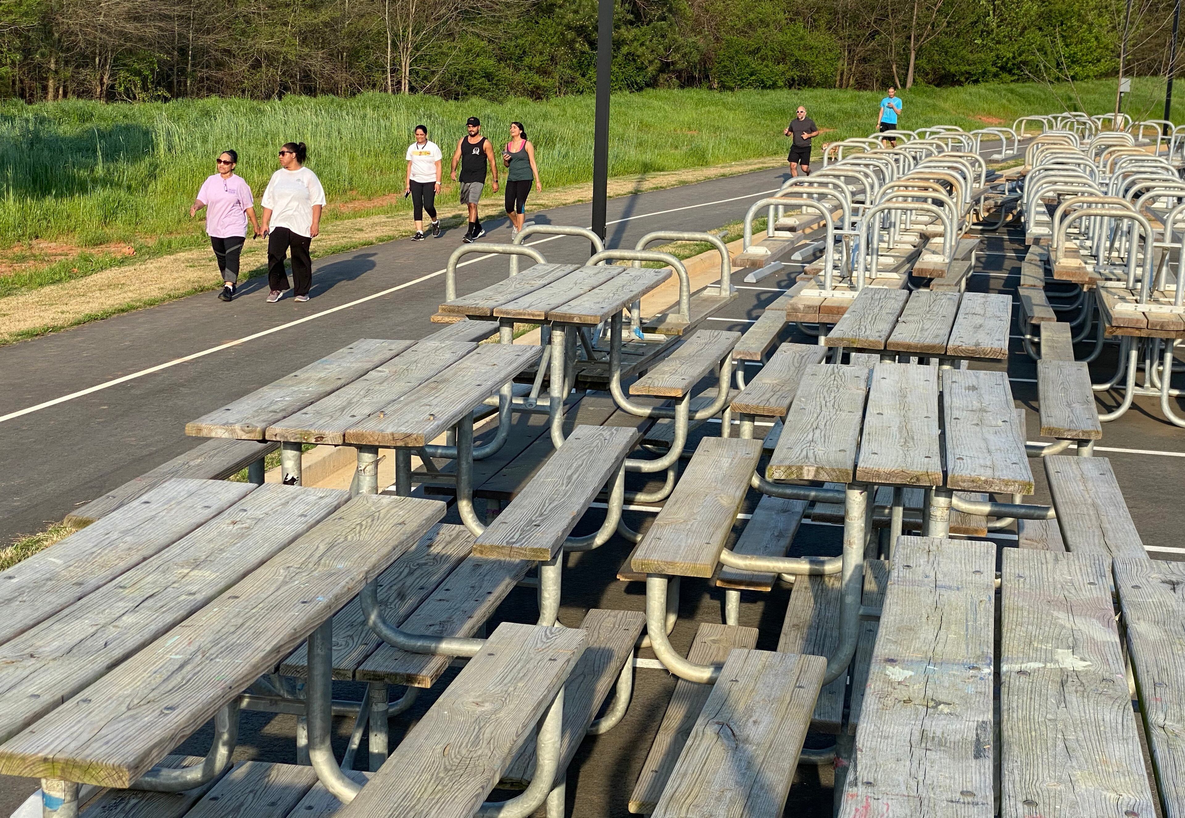March 27, 2020 Lawrenceville - Gwinnett residents walk past a pile of wooden public picnic tables at Alexander Park on Friday evening, March 27, 2020. Gwinnett County and its 16 cities have issued a stay-at-home order for residents that goes into effect at 12:01 a.m. Saturday. (Hyosub Shin / Hyosub.Shin@ajc.com)