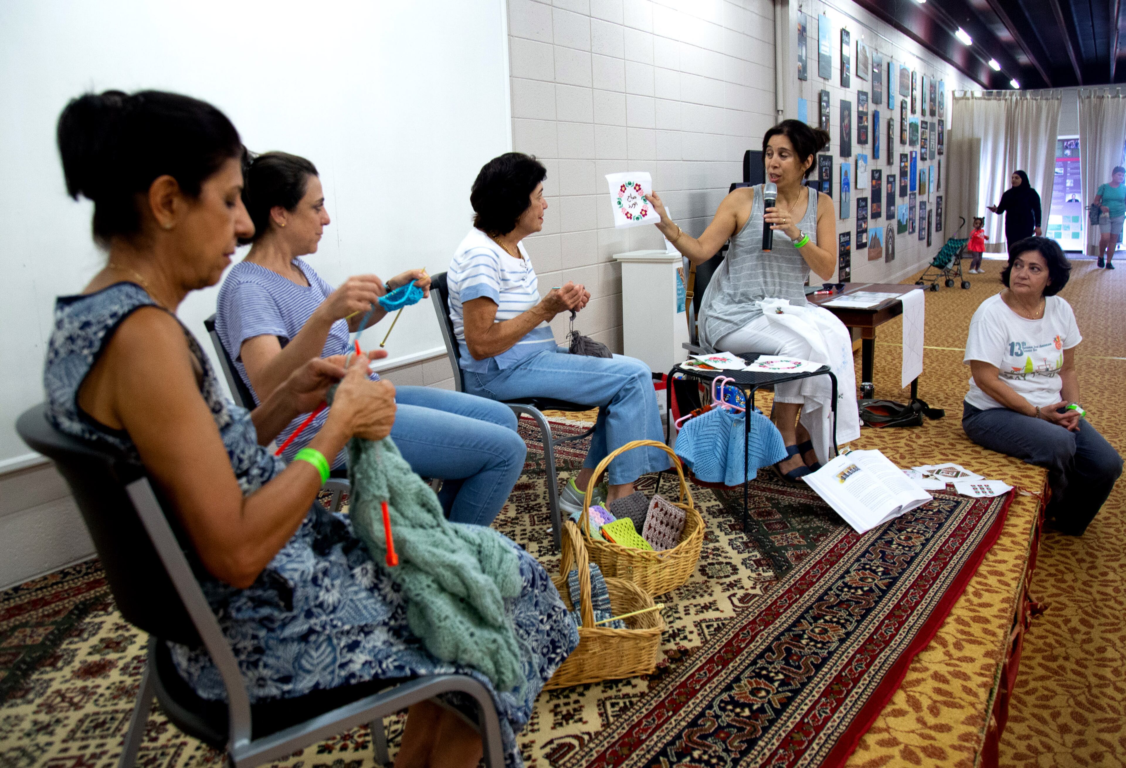 Angela Khoury from the Knit & Stitch Club at the Alif Institute holds up examples of traditional stitch work during a demonstration at the 14th annual Atlanta Arab Festival in on Sunday, September 15, 2019. STEVE SCHAEFER / SPECIAL TO THE AJC