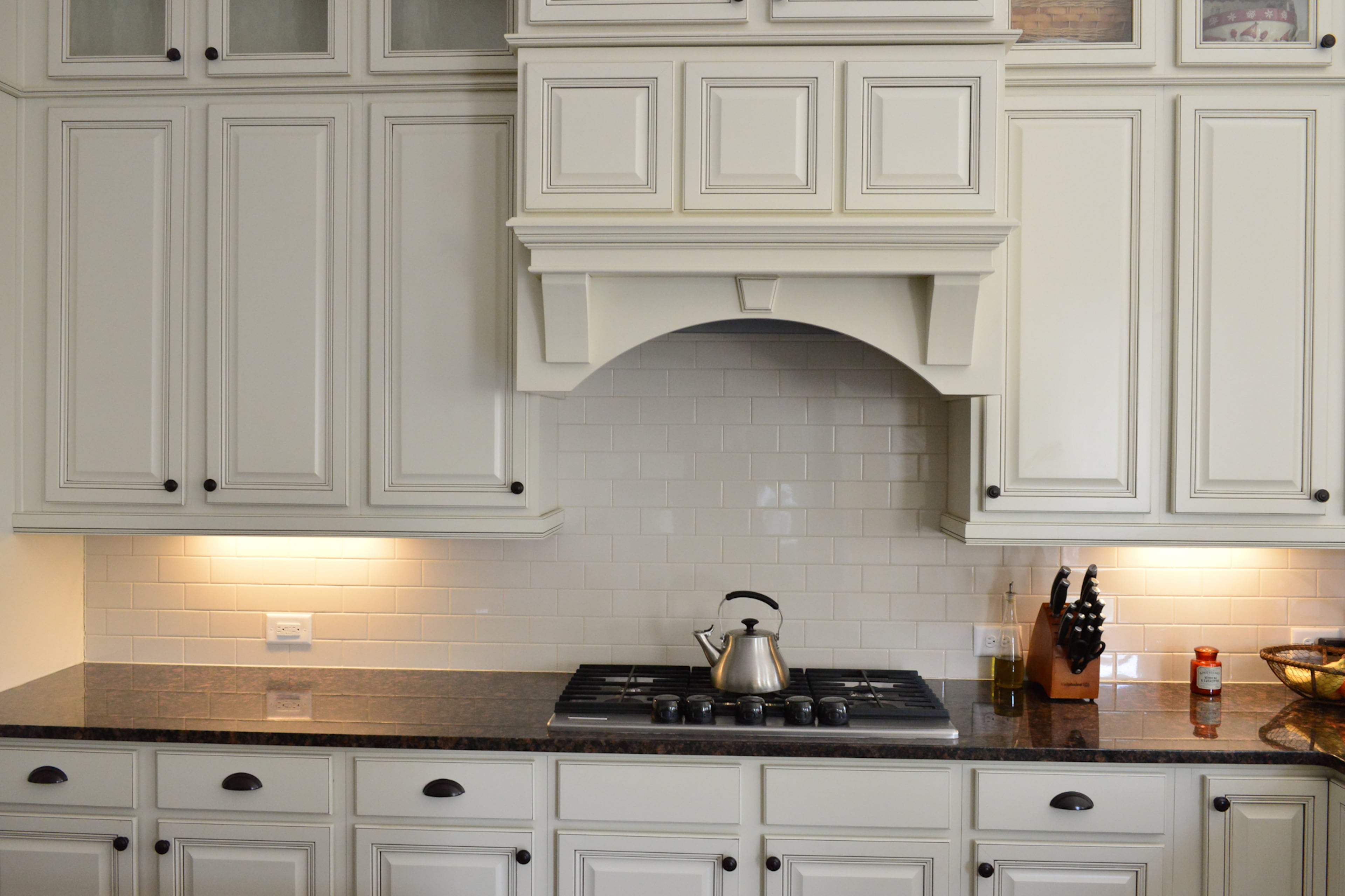 Soft white custom cabinets with a glazed overlay offers ample storage for homeowners Justin and Sophia DeCouto in their new house built by Edward Andrews Homes. The new kitchen also features KitchenAid stainless steel appliances, soft-close drawers, undercabinet lighting and tan granite countertops.