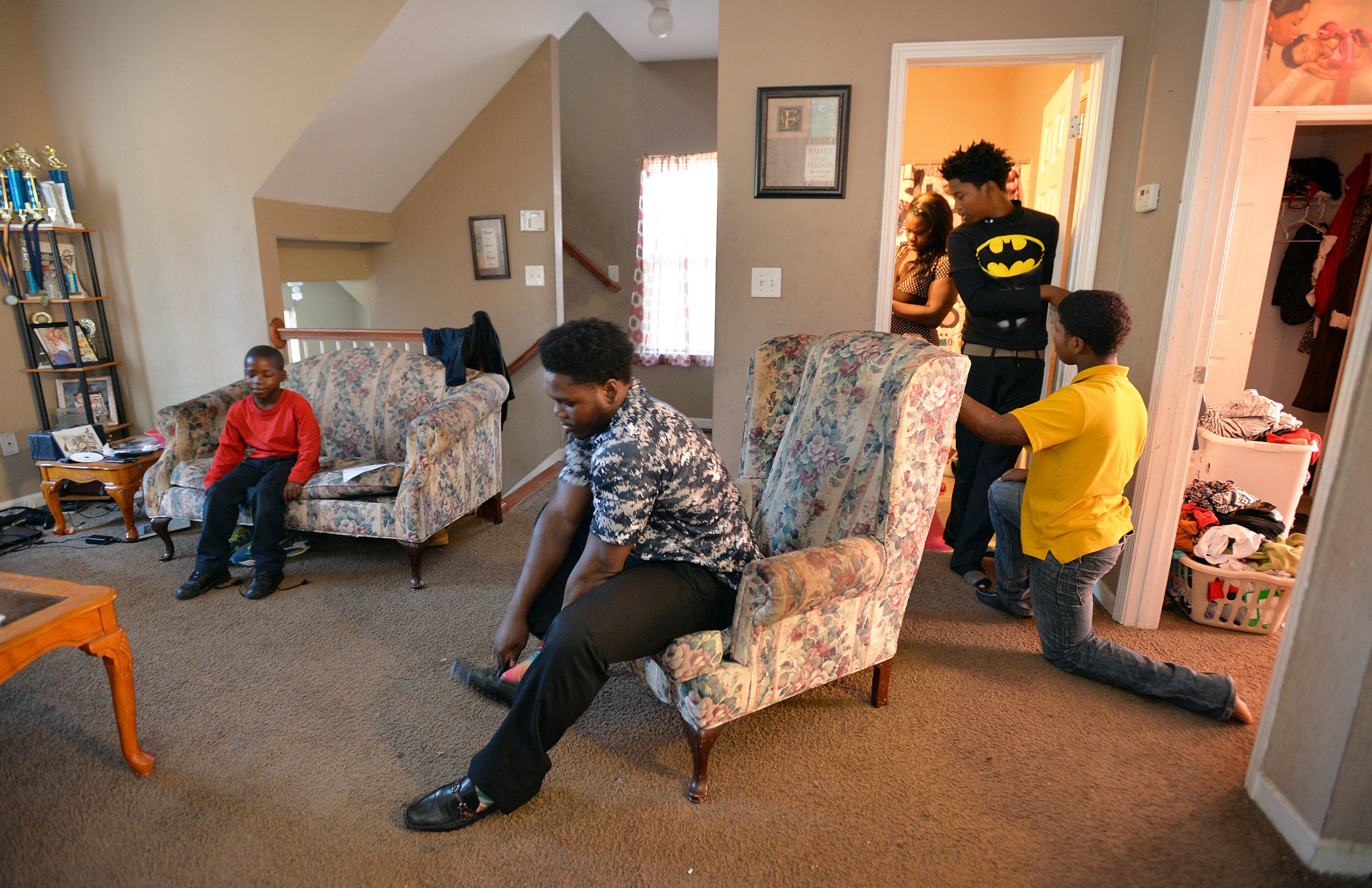 Ashley Roberson (background) and her brothers (from left) Damyuss, 8, Darius, 18, Dayzhon, 15, and Dazmine, 12, get ready to go to church. HYOSUB SHIN / HSHIN@AJC.COM