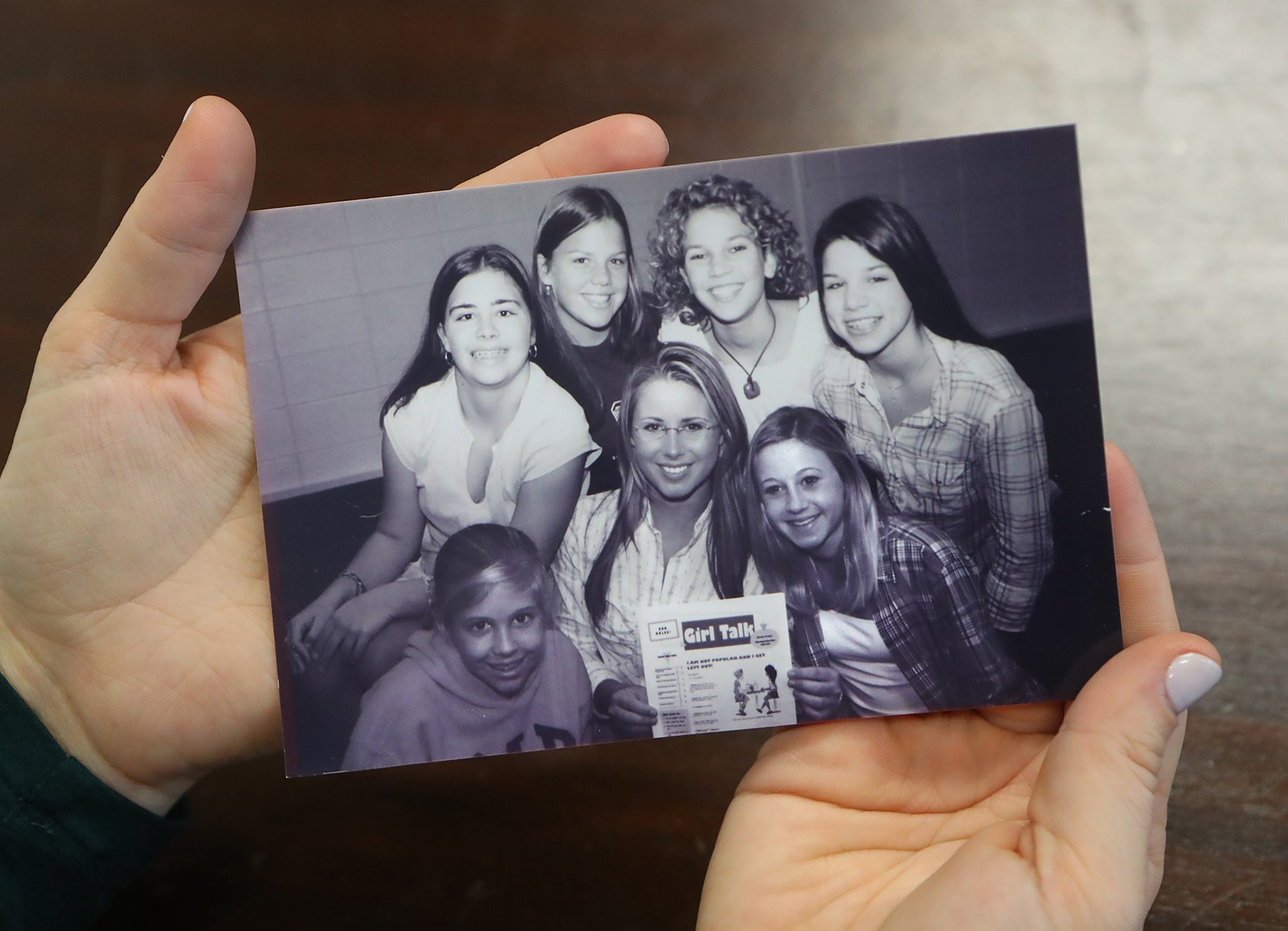 During an interview on Jan. 4, 2017, Girl Talk founder Haley Kilpatrick holds a 2002 photograph of the first Girl Talk chapter meeting that happened at the Deerfield-Windsor Middle School in Albany. (At bottom right are Kilpatrick and her sister, Kelly.) CURTIS COMPTON / CCOMPTON@AJC.COM