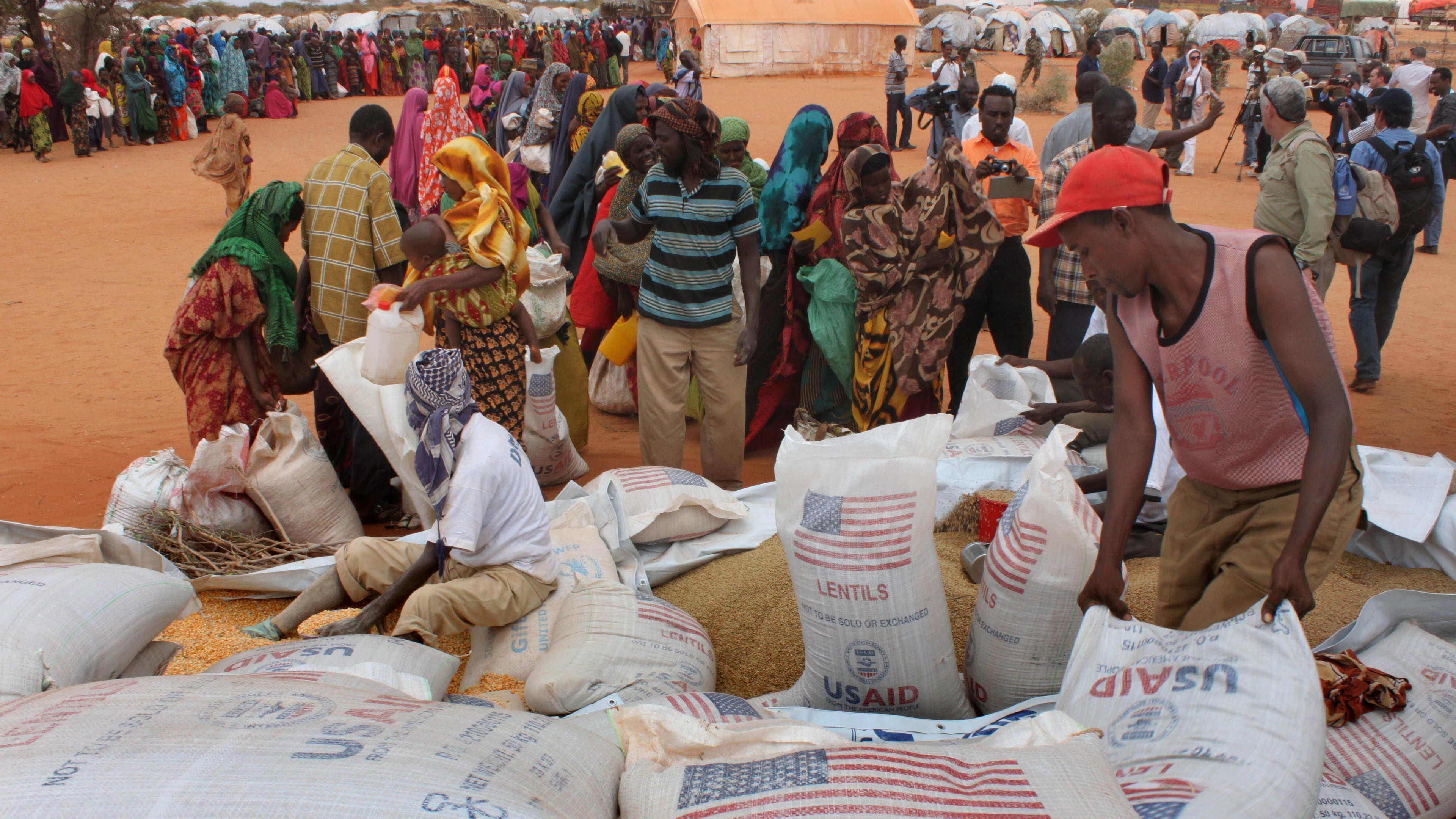 FILE - Workers distribute food aid from the World Food Program at a refugee camp in Dolo, Somalia on July 18. 2012. (AP Photo/Jason Straziuso, file)
