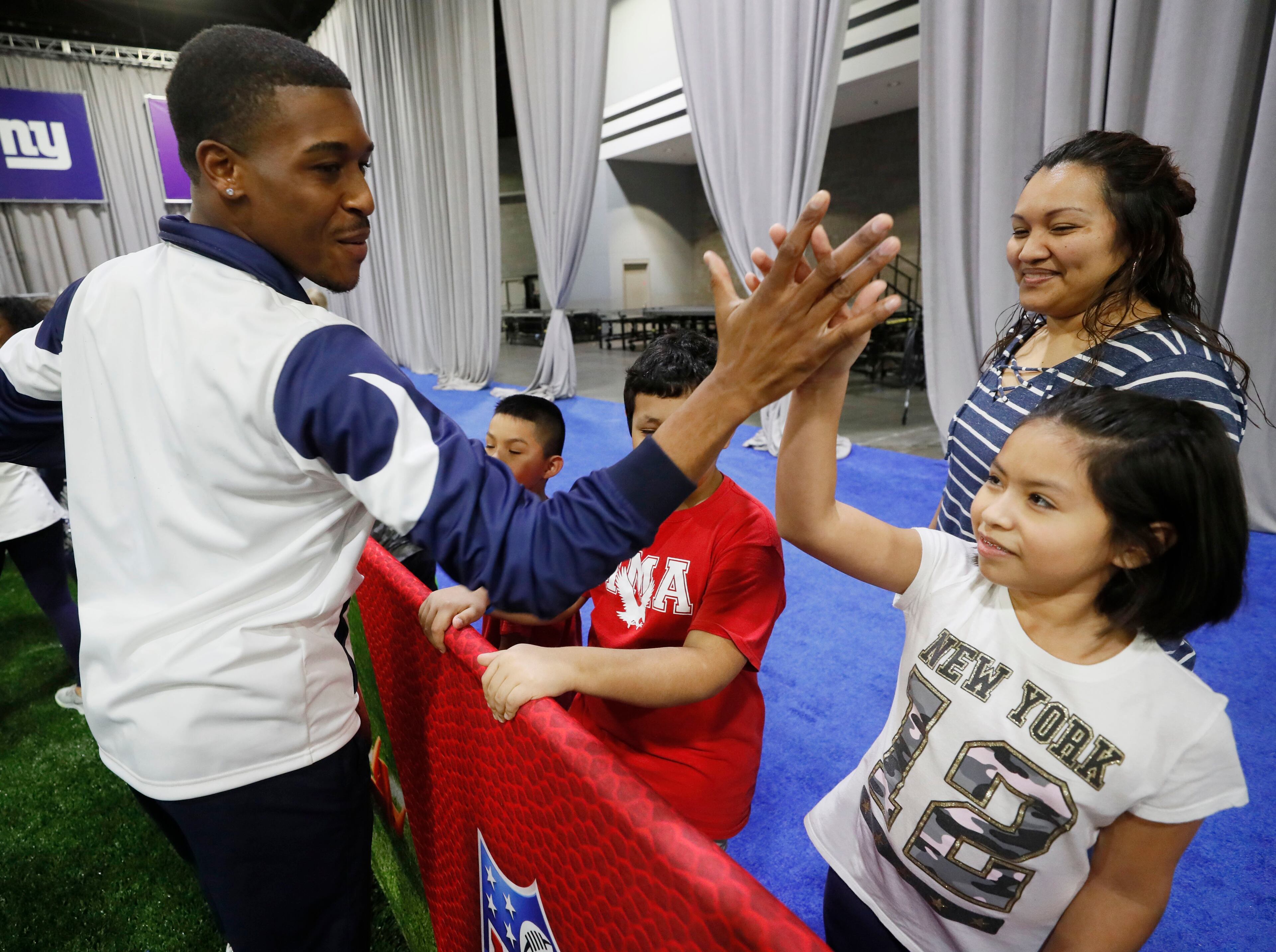 1/28/19 - Atlanta - REPORTER QUOTED - Quinton Peron, a Los Angeles Rams cheerleader, gives a high five to Alana Reyes, 9, from Mundy Mill Learning Academy in Gainesville, as she enters the camp. . Her mother, Jenny Reyes is behind her.. During Super Bowl Week, the NFL hosts PLAY 60, a national youth health and fitness campaign focused on encouraging kids to be active for at least 60 minutes a day. On Monday, PLAY 60 hosted 300 mostly Hispanic children for an activity session led by Pro Football Hall of Fame offensive tackle Anthony Muoz. Bob Andres / bandres@ajc.com