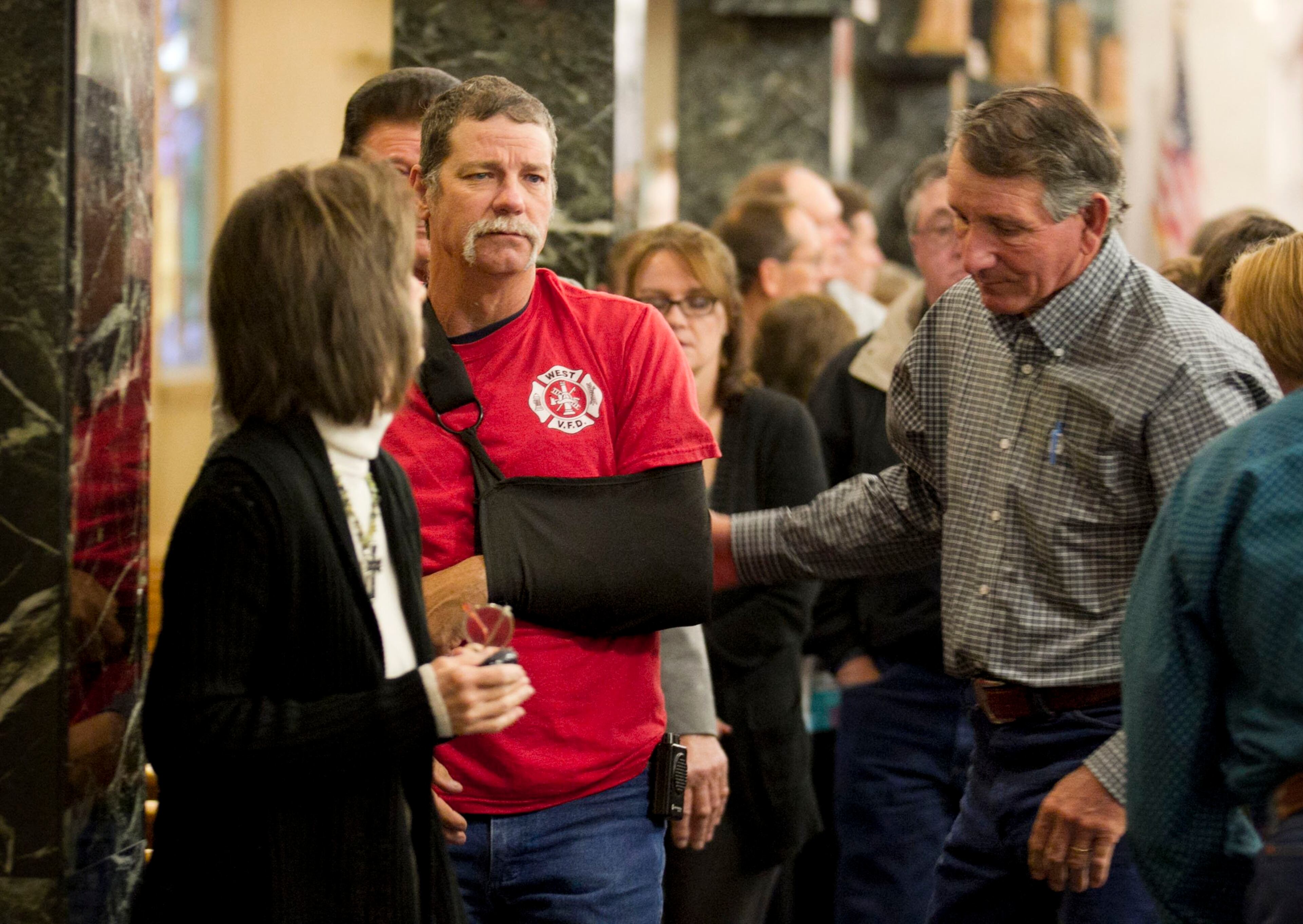 A man with an injured arm and wearing a West V.F.D. t-shirt attends a worship service at Assumption Catholic Church in West on Sunday April 21, 2013, days after a fertilizer plant explosion killed 14 people, including several West V.F.D. firefighters.