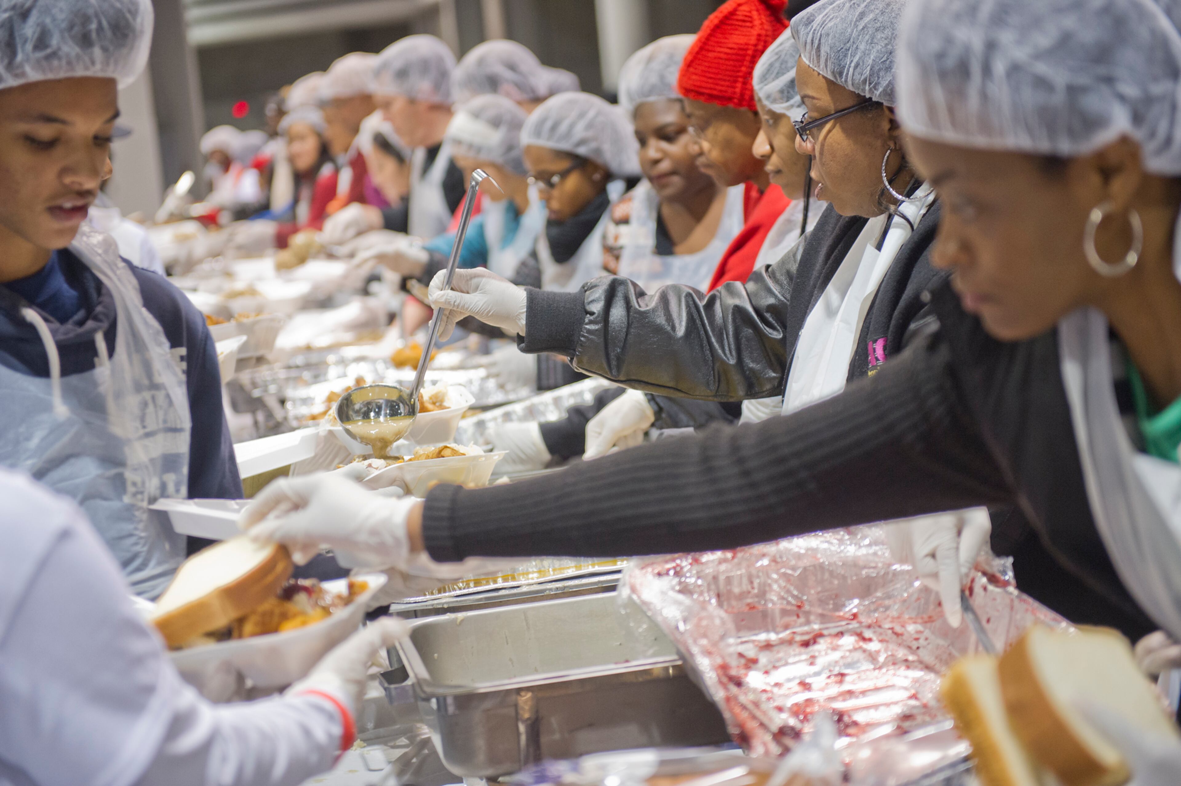 Janet Jack (right), one of hundreds of volunteers, pours gravy on a tray of food during the Hosea Feed the Hungry and Homeless annual Thanksgiving meal at the Georgia World Congress Center in Atlanta on Nov. 28, 2013.