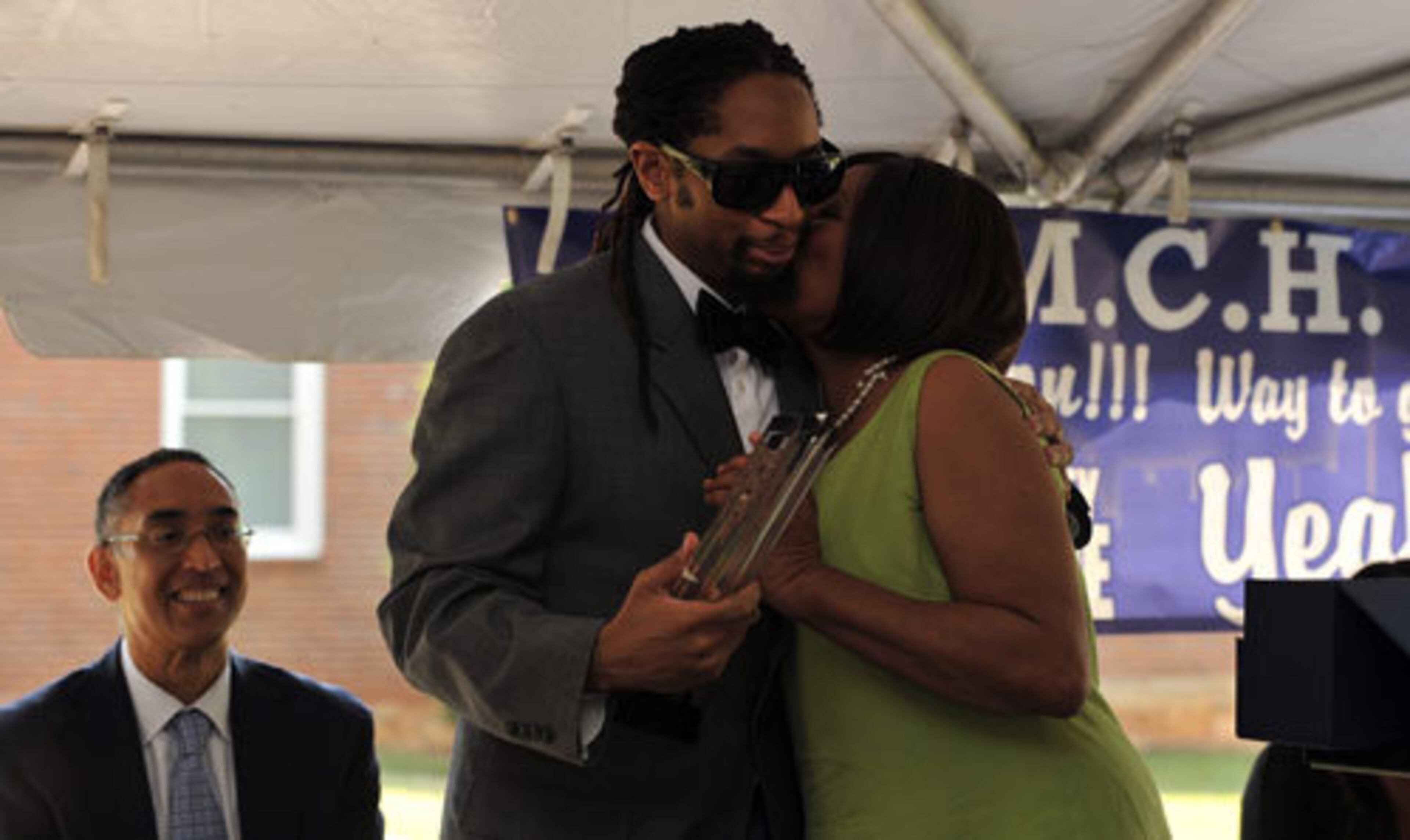 Lil Jon gets a kiss from his mother, Carrie Smith-Williams, after she presented him with an award at the United Methodist Children's Home. In the background is Dekalb County CEO Burrell Ellis.