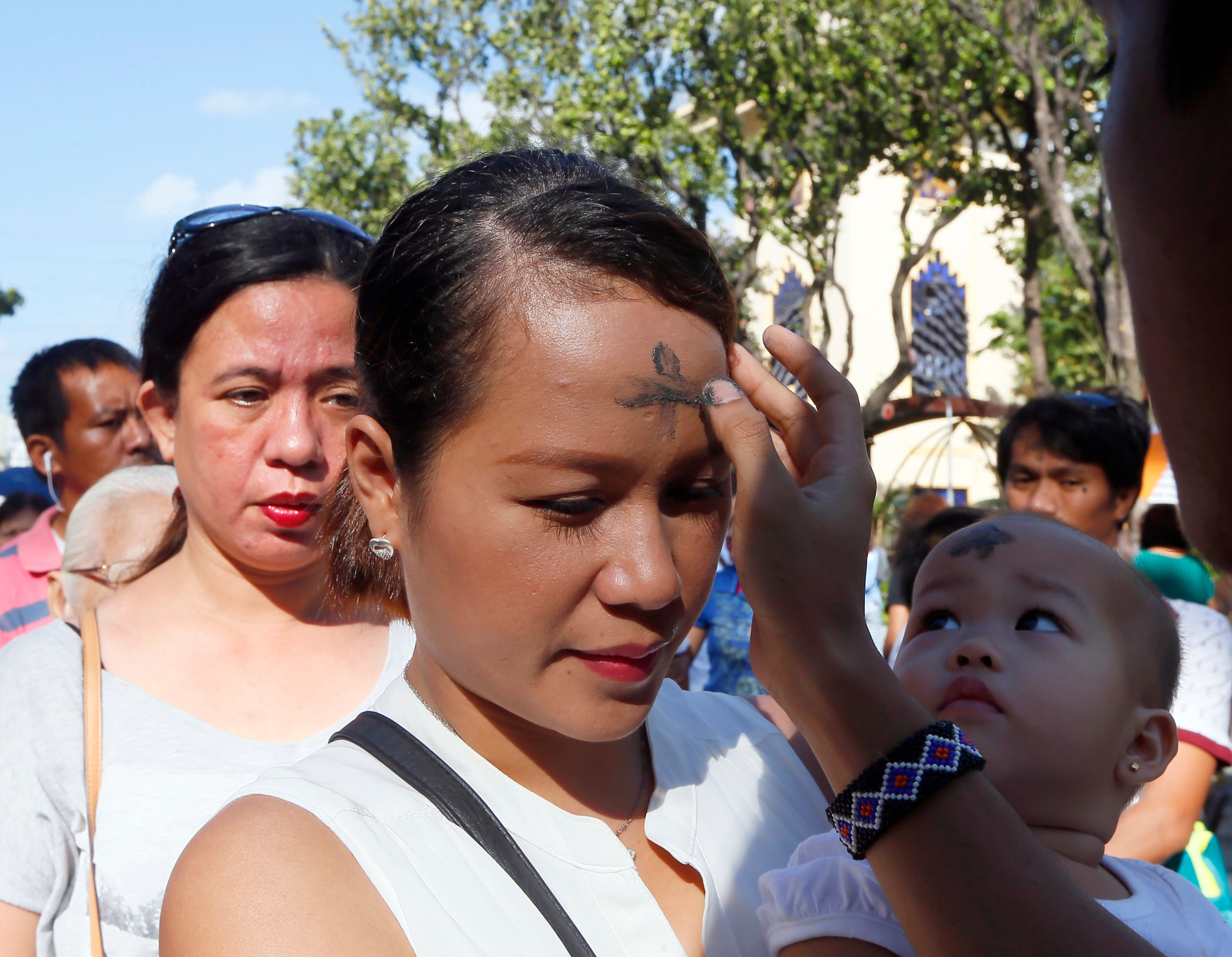 A lay minister marks a sign of the cross on the forehead of a Roman Catholic worshipper using ashes from burnt palm leaves in observance of Ash Wednesday at suburban Paranaque city, south of Manila,Philippines Wednesday, Feb. 10, 2016. Ash Wednesday ushers the 40-day season of Lent and is observed among Roman Catholics to remind mankind of being mortals.(AP Photo/Bullit Marquez)
