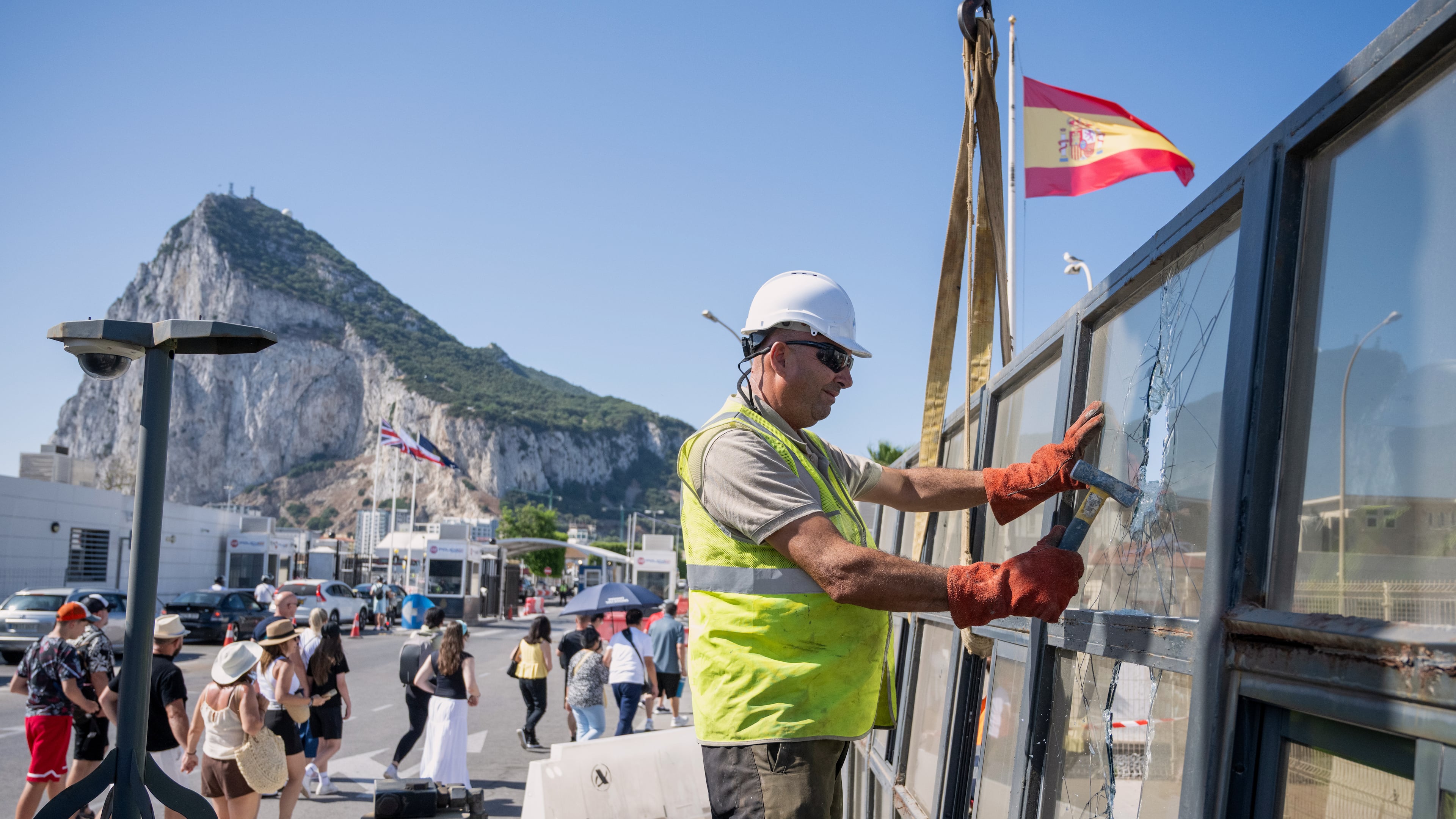 Against the backdrop of the Rock of Gibraltar, workers dismantle a Spanish border checkpoint that separated the disputed British overseas territory from Spain in La Línea de la Concepción, Spain, Monday, July 6, 2026. (AP Photo/Marcos Moreno)