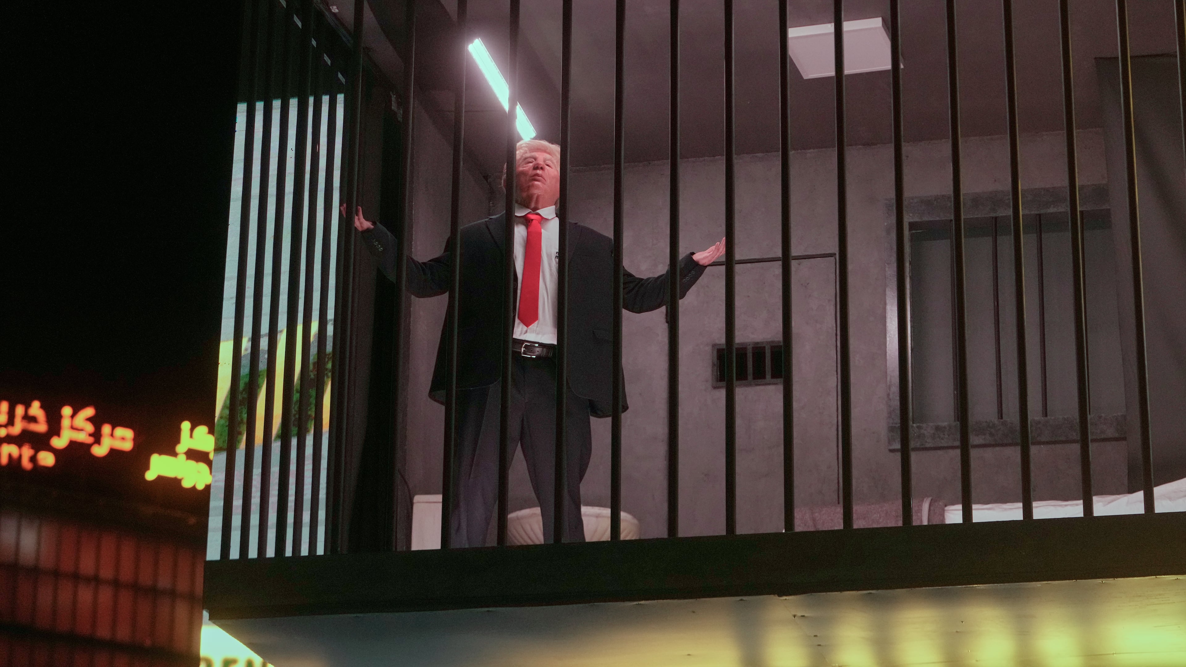 An actor portraying U.S. President Donald Trump sits behind bars in a billboard installation resembling a prison cell in Tajrish Square in Tehran, Iran, Wednesday, Oct. 21, 2026. (AP Photo/Vahid Salemi)