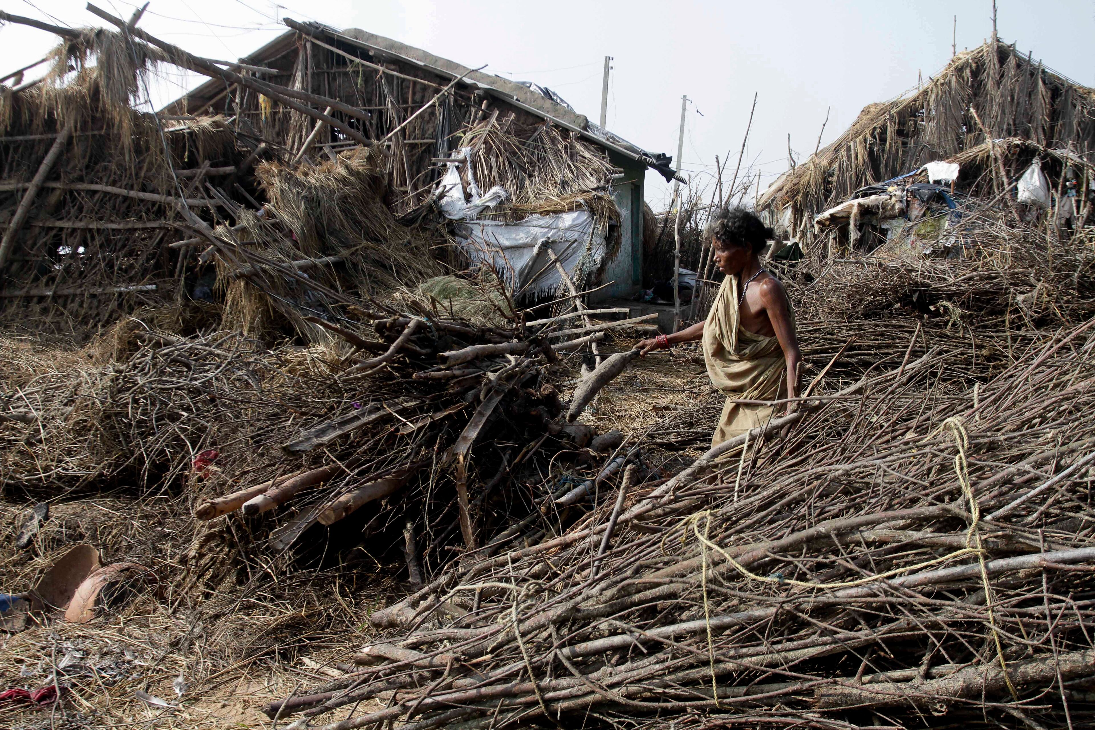An Indian woman walks past damaged houses after returning to a cyclone-hit village in Pudumpeta, Ganjam district, Orissa state, India, Monday, Oct. 14, 2013. A mass government evacuation of nearly 1 million people spared India the widespread deaths many had feared from the powerful weekend cyclone, which destroyed hundreds of millions of dollars' worth of crops and tens of thousands of homes. (AP Photo/Bikas Das)
