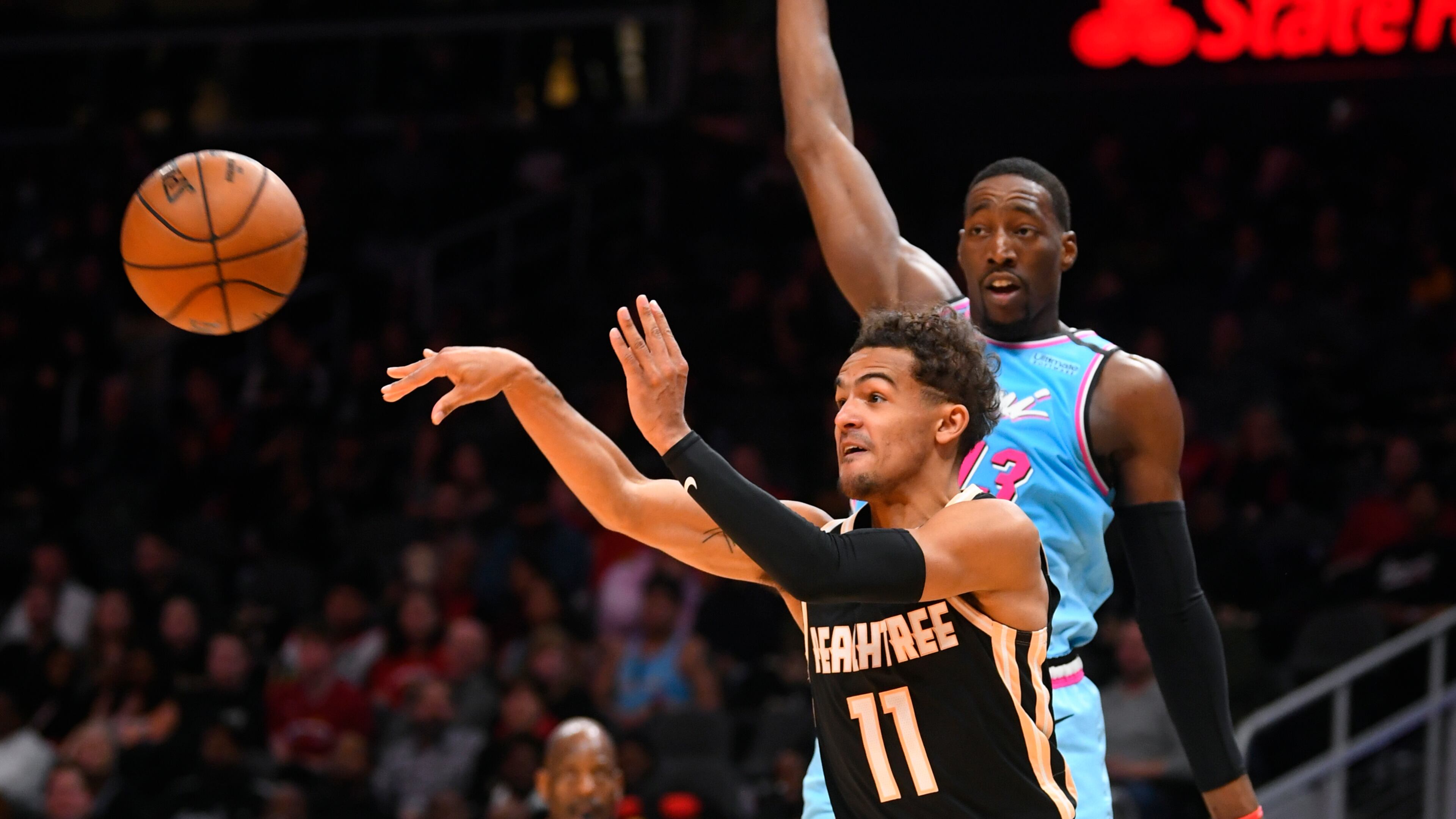Hawks guard Trae Young passes as Heat forward Bam Adebayo defends Thursday's Atlanta-Miami game at State Farm Arena. (AP photo/John Amis)