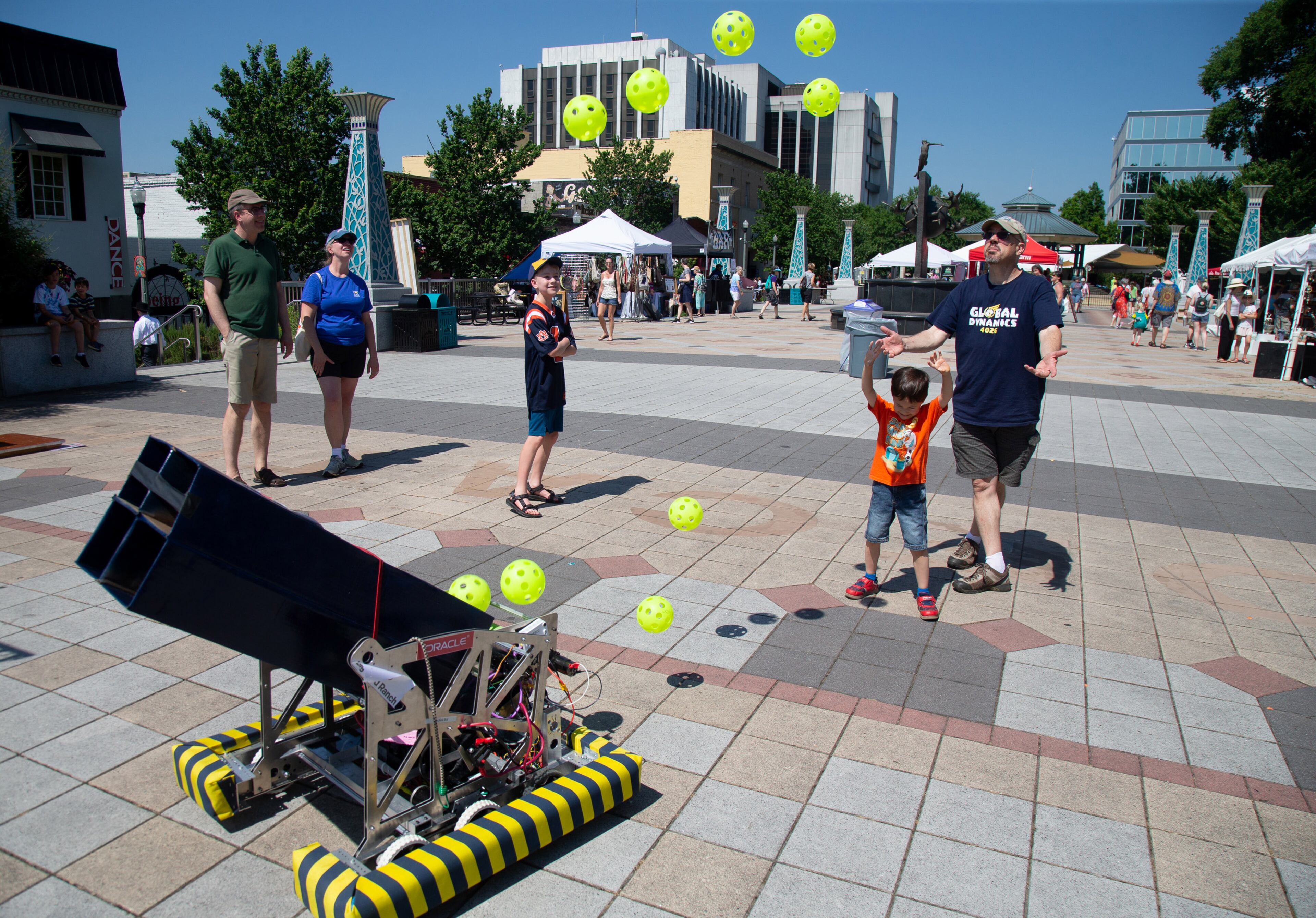 Fairgoers try and catch plastic balls shot out of a robot built by the Decatur Robotics club during the annual Decatur Arts Festival on Sunday, May 26, 2019. STEVE SCHAEFER / SPECIAL TO THE AJC
