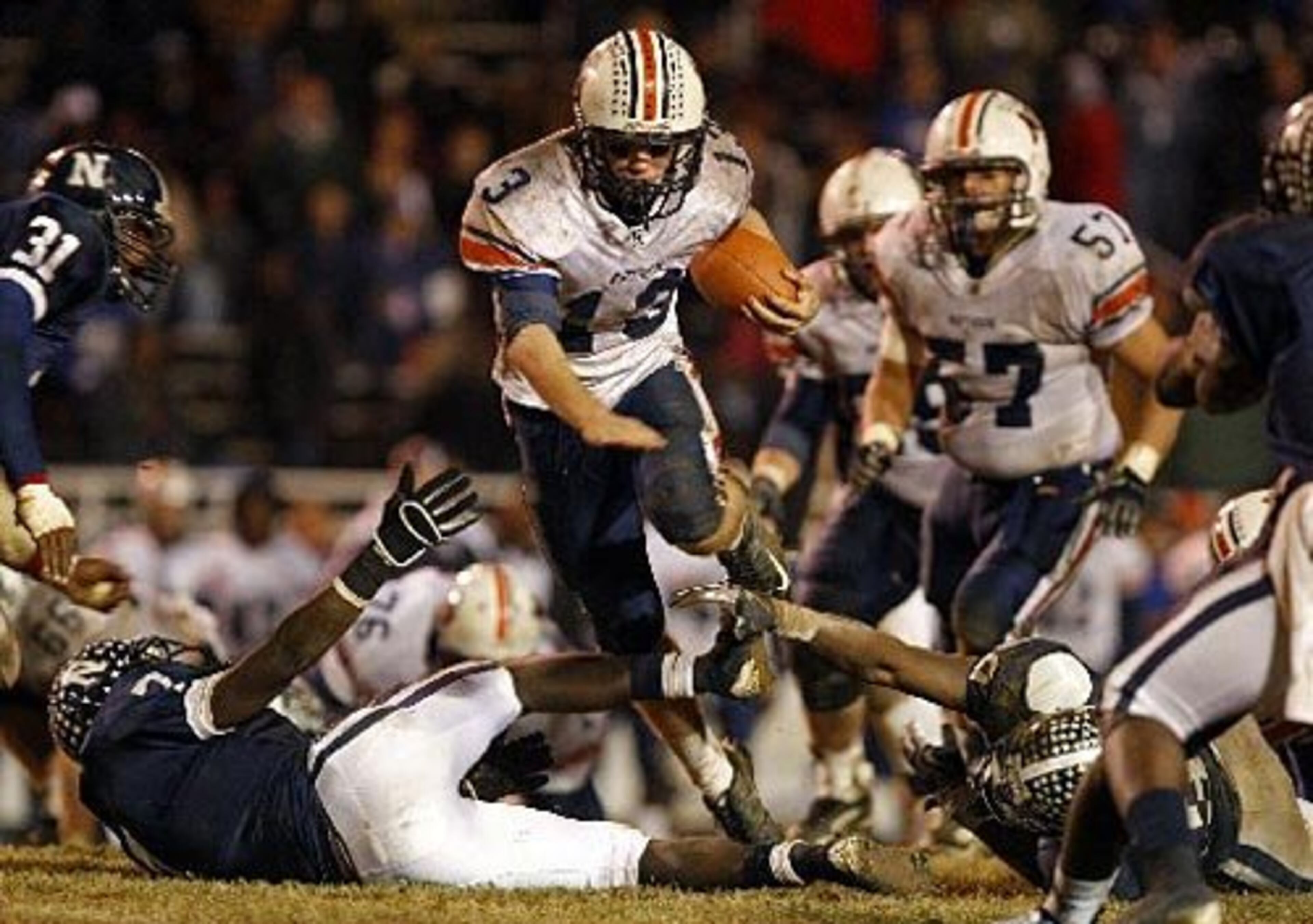 Northside-Warner Robins quarterback Briar Van Brunt (13) runs for a first down as he jumps over Newnan defenders Alberry Melson (7, left) and Alec Ogletree (39, right) during the fourth quarter.
