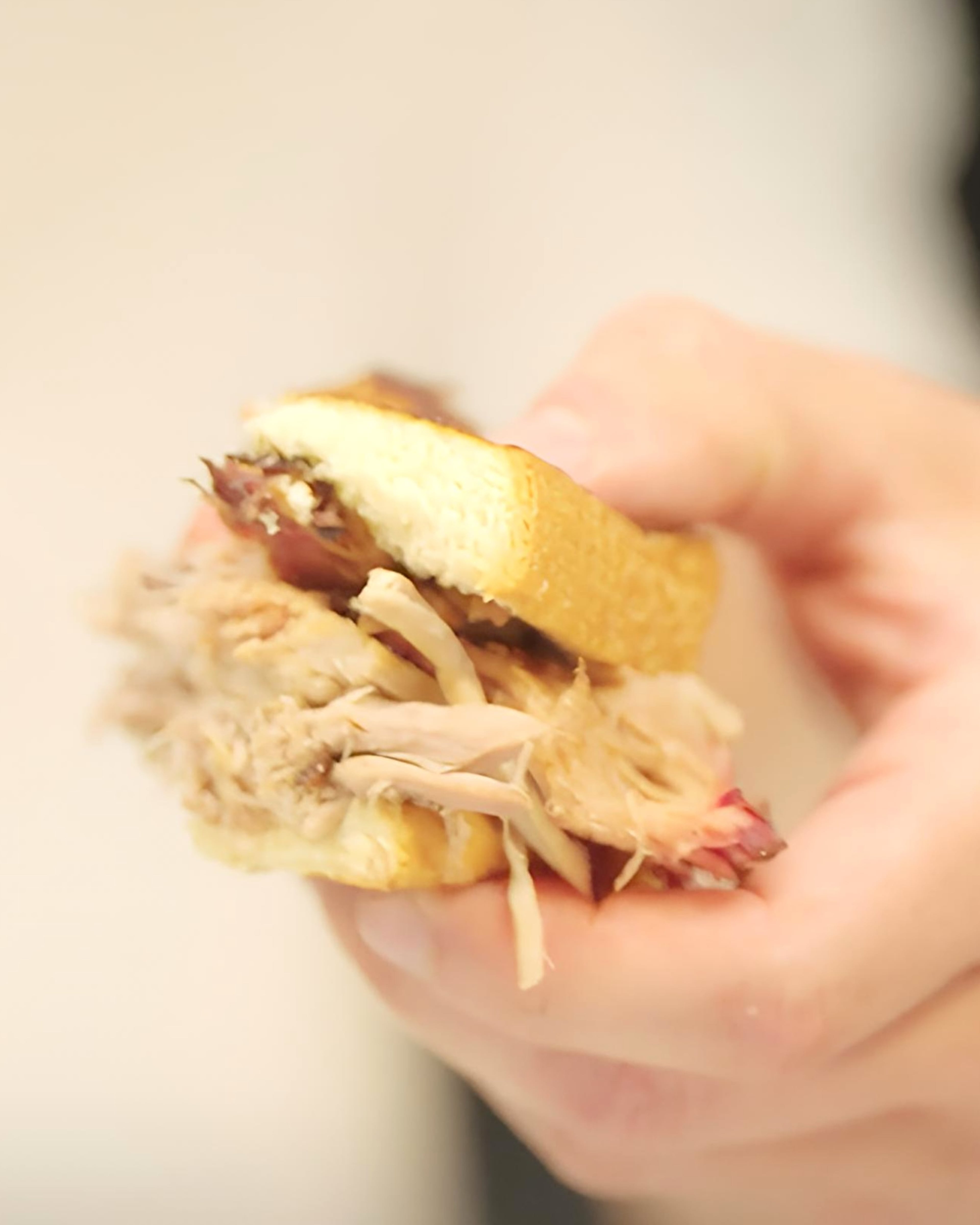 An AJC taste tester holds a quarter of a pulled pork sandwich. (Jordan Pettiford/AJC)