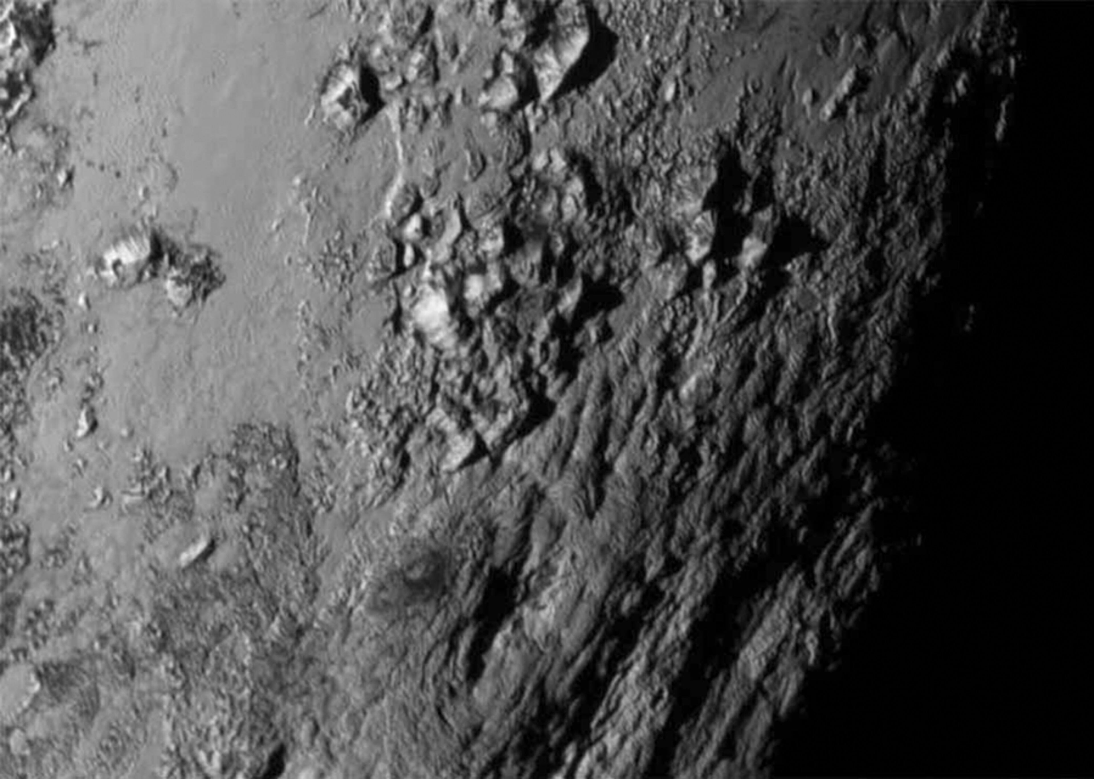 A handout photo provided by NASA taken early on Tuesday morning (July 15, 2015) by NASA's New Horizons spacecraft shows a small portion of Pluto's surface, with mountains up to 11,000 feet high. A day after its successful flyby, NASA's New Horizons spacecraft, which spent nine years and traveled three billion miles to study the dwarf planet, sent back the first close-up photographs of Pluto and its largest moon, Charon. (NASA via The New York Times) '