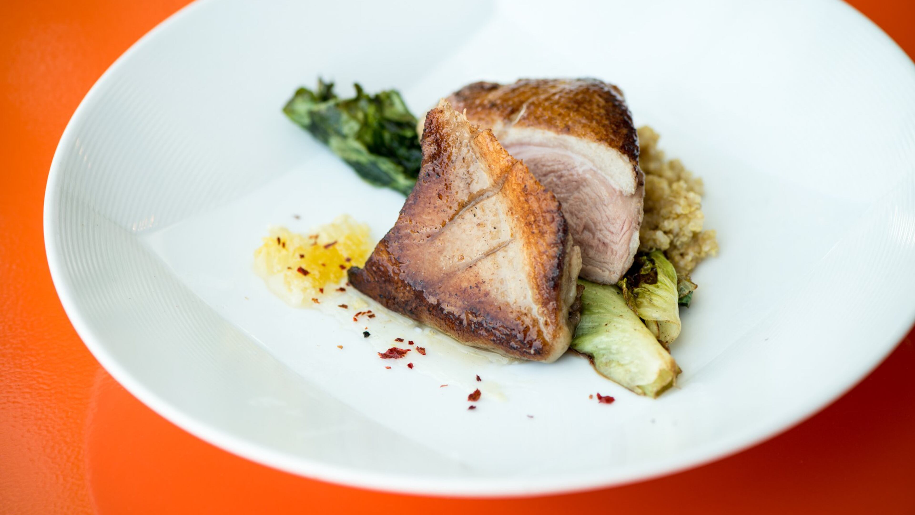 Expat Fowl entree, duck with grilled escarole, Calabrian chili honey, and quinoa. Photo credit- Mia Yakel.