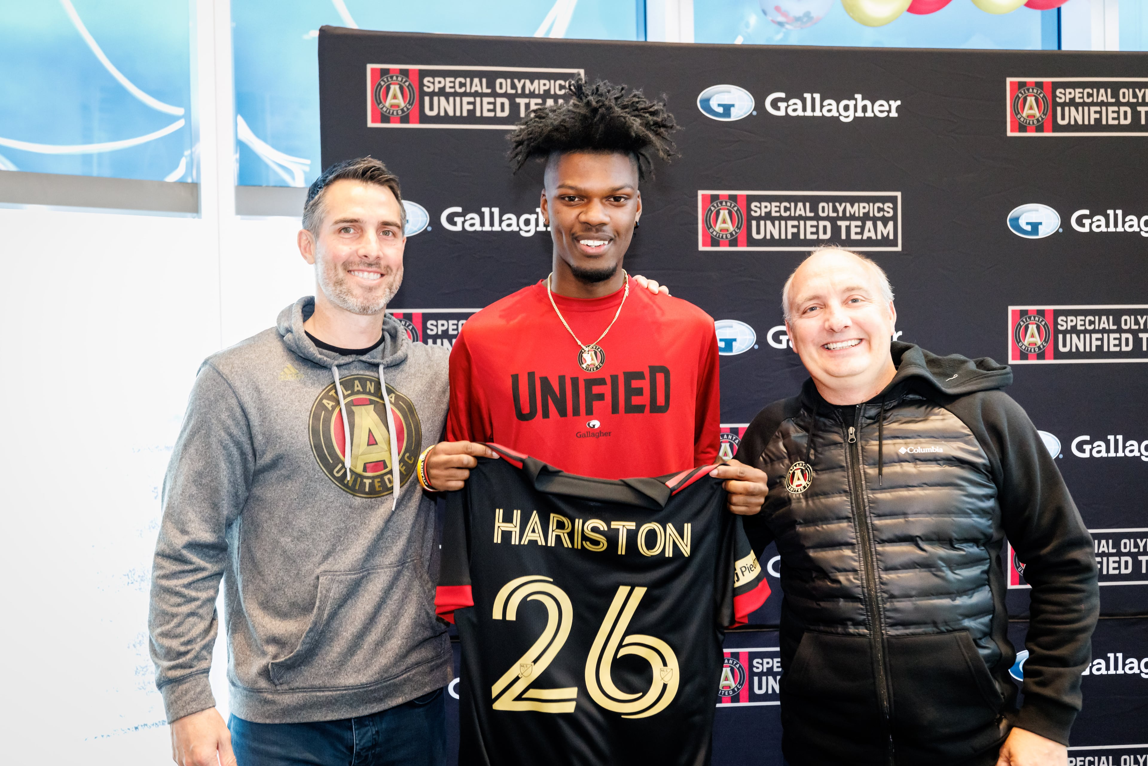Special Olympics Unified Team member Xavier Hairston holds his soccer jersey during signing day. Atlanta United Technical Director Carlos Bocanegra (left) and team President Darren Eales are also pictured. Credit: Karl L. Moore/Atlanta United