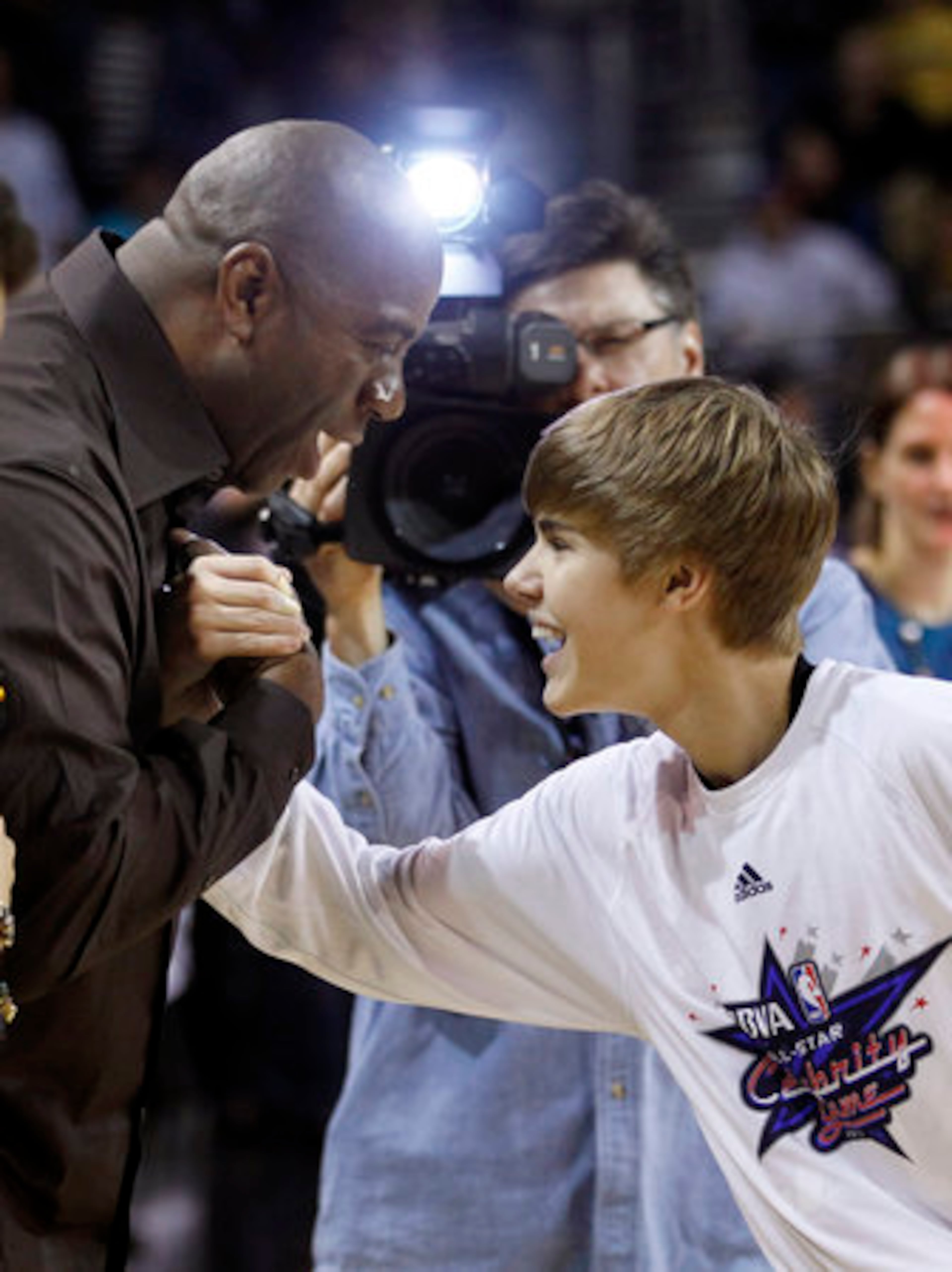 Singer Justin Bieber, right, shakes hands with former NBA basketball player Magic Johnson before a BBVA All-Star celebrity basketball game at the NBA All Star Weekend in Los Angeles, Friday, Feb. 18, 2011.