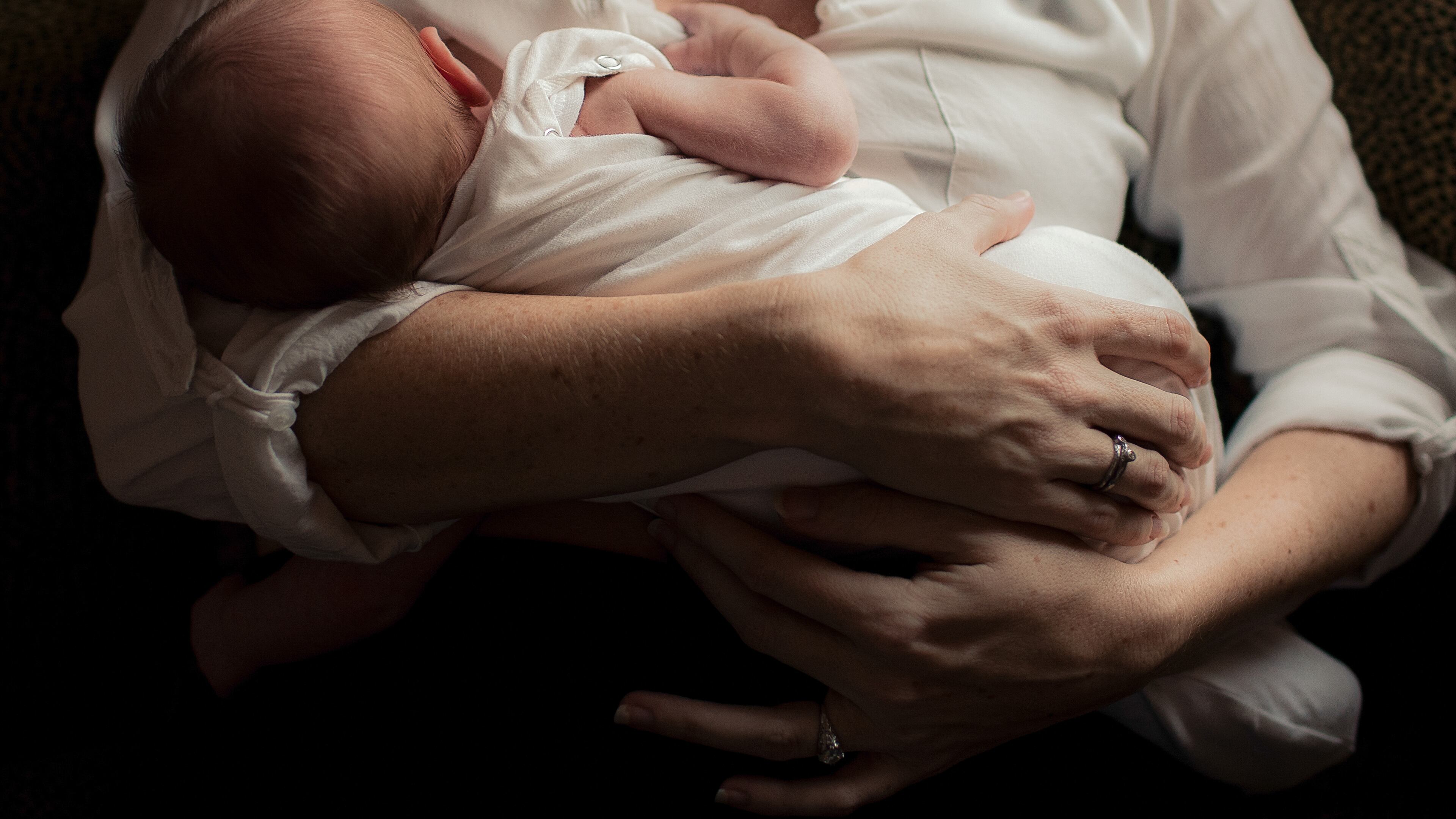Mother holding newborn baby in arms (stock photo)
