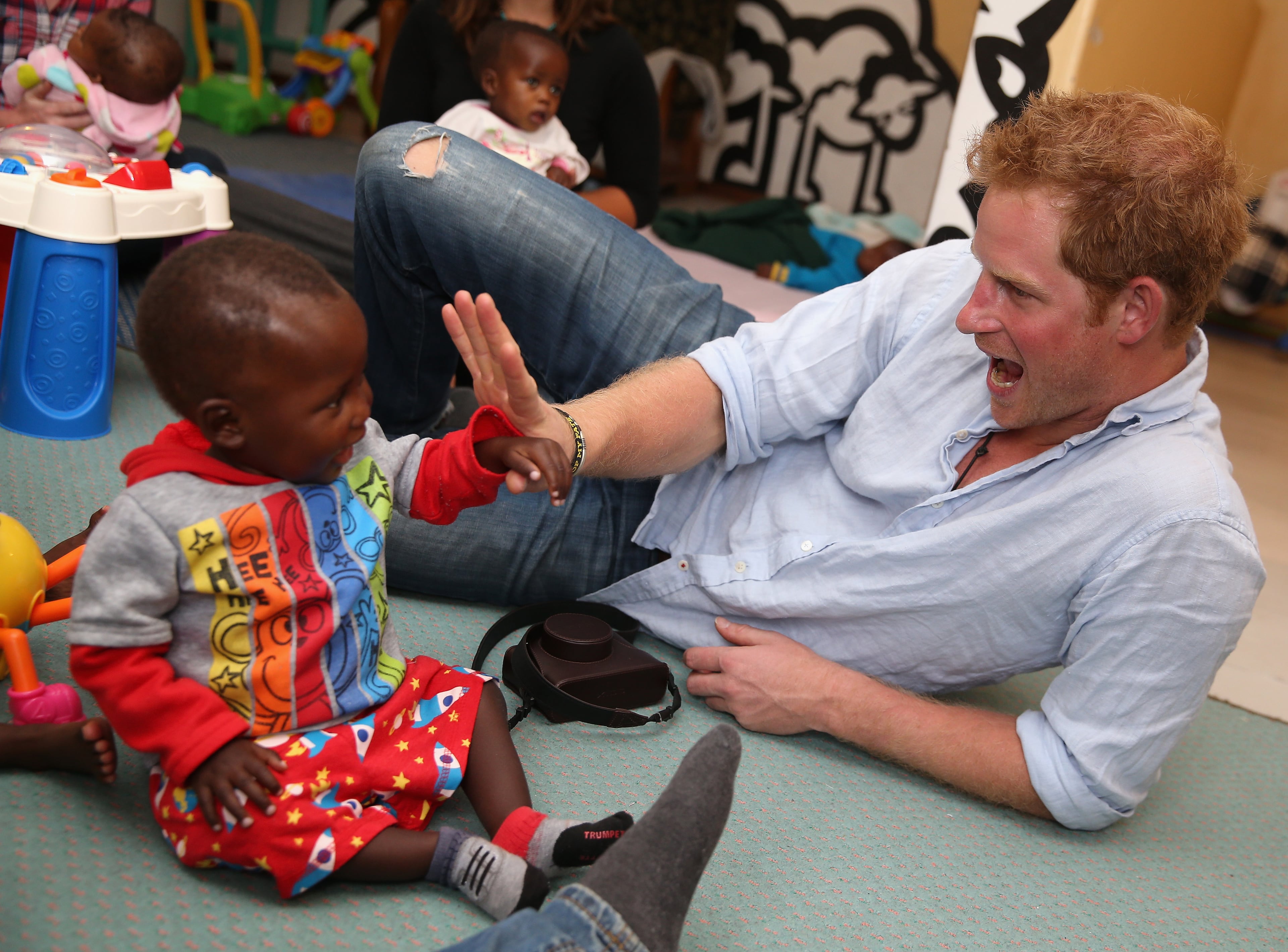 Prince Harry plays with two young children (who are going through a programme for malnourishment) during a visit to the organisation supported by Sentebale 'Touching Tiny Lives' on December 8, 2014 in Mokhotlong, Lesotho. Prince Harry was visiting Lesotho to see the work of his charity Sentebale. Sentebale provides healthcare and education to vulnerable children in Lesotho, Southern Africa. The particular theme of his visit was to check on the progress of the Mamohato Childrens Centre which will provide vital support to children affected by HIV. Prince Harry founded Sentebale (which means Forget Me Not in Sesotho) with Prince Seeiso in 2006. (Photo by Chris Jackson/Getty Images for Sentebale)