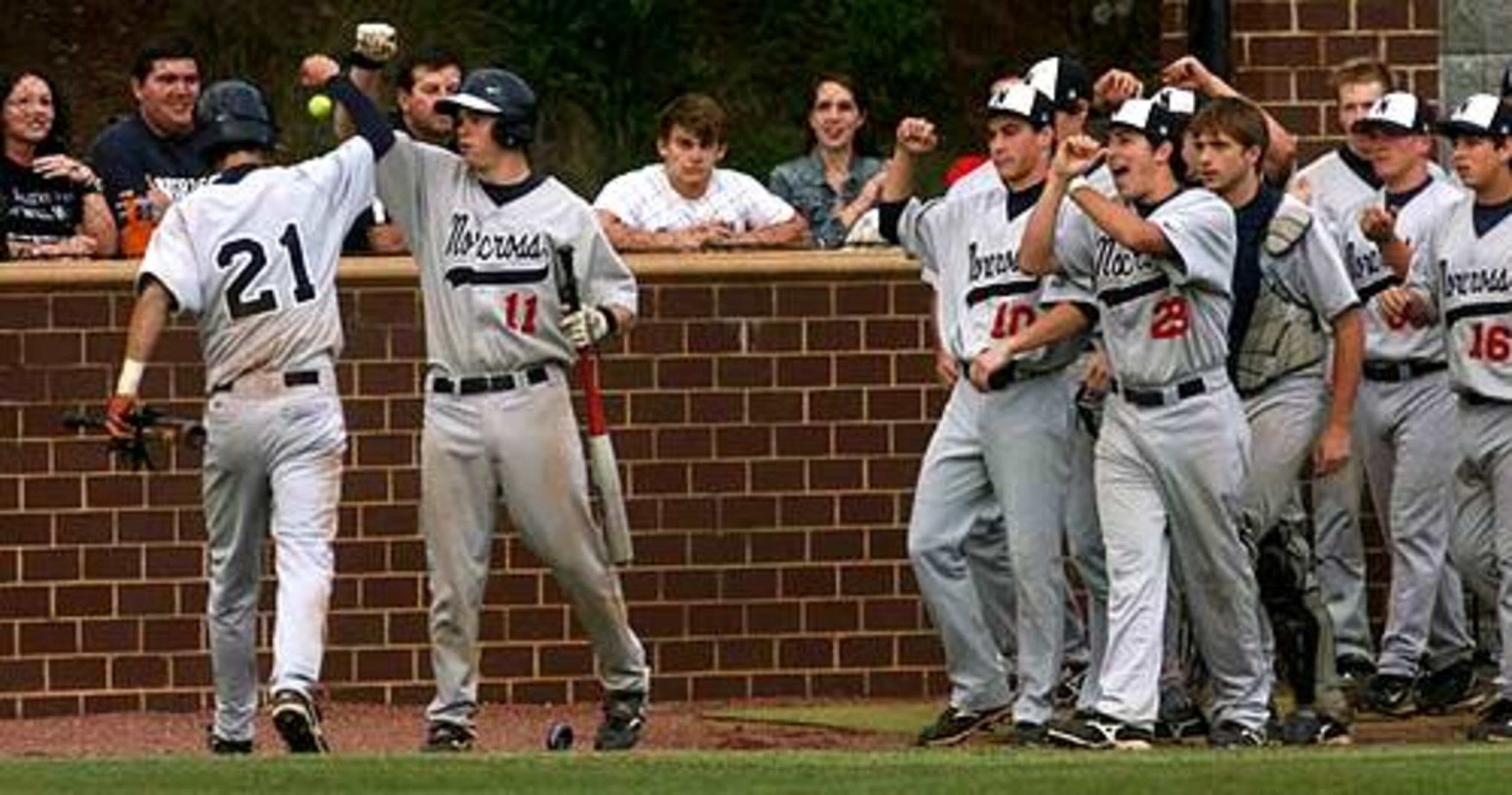 Norcross' Travis Ragsdale (21) and Drew Lennox (11) celebrate with their teammates after Ragsdale crosses home plate to tie the game 2-2.