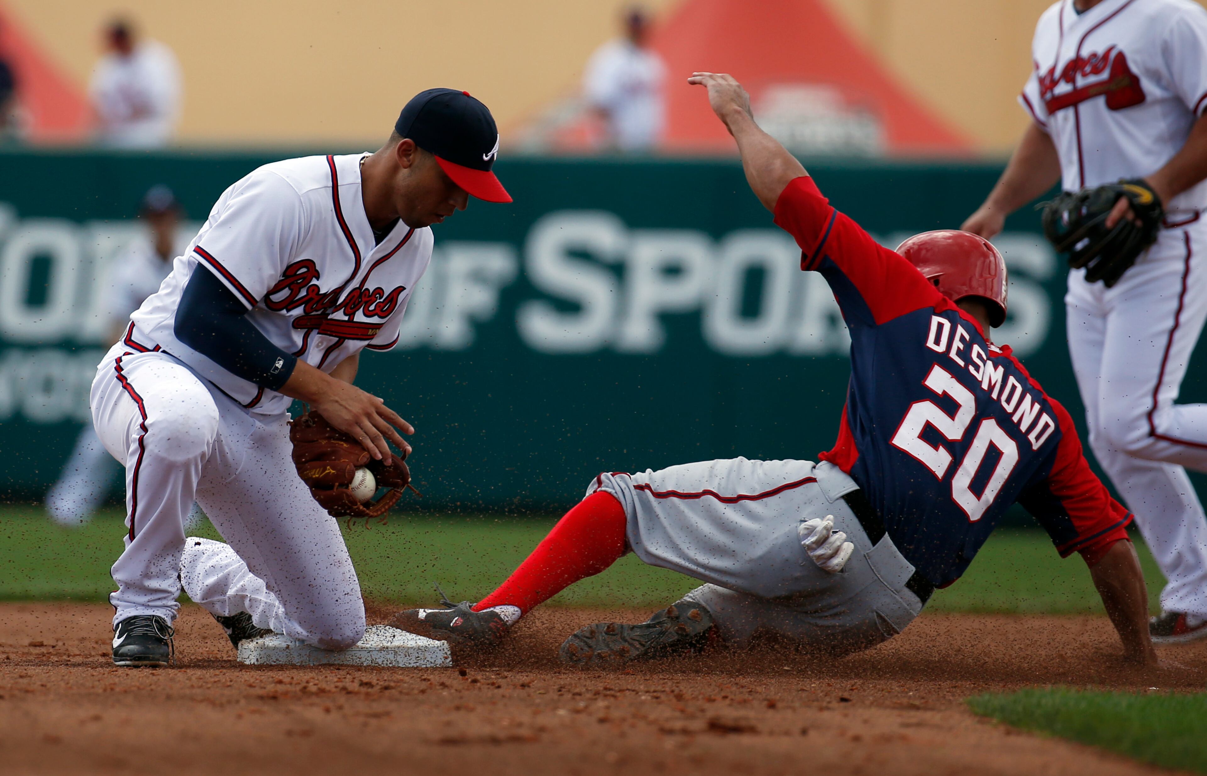Washington Nationals' Ian Desmond (20) is safe at second base on the steal as Atlanta Braves shortstop Andrelton Simmons bobbles the throw, in the fourth inning of a spring exhibition baseball game, Tuesday, March 4, 2014, in Kissimmee, Fla.