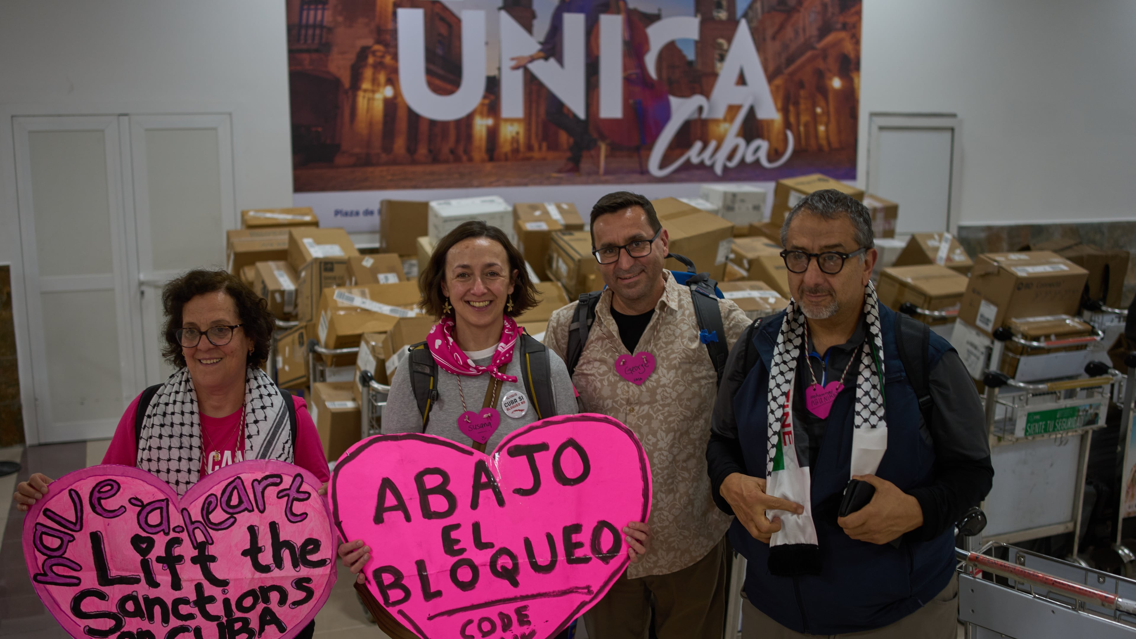 CODEPINK activists hold signs in front of boxes of aid they brought as part of the "Nuestra America," or Our America Convoy, after landing at the airport in Havana, Cuba, Friday, March 20, 2026. (AP Photo/Ramon Espinosa)