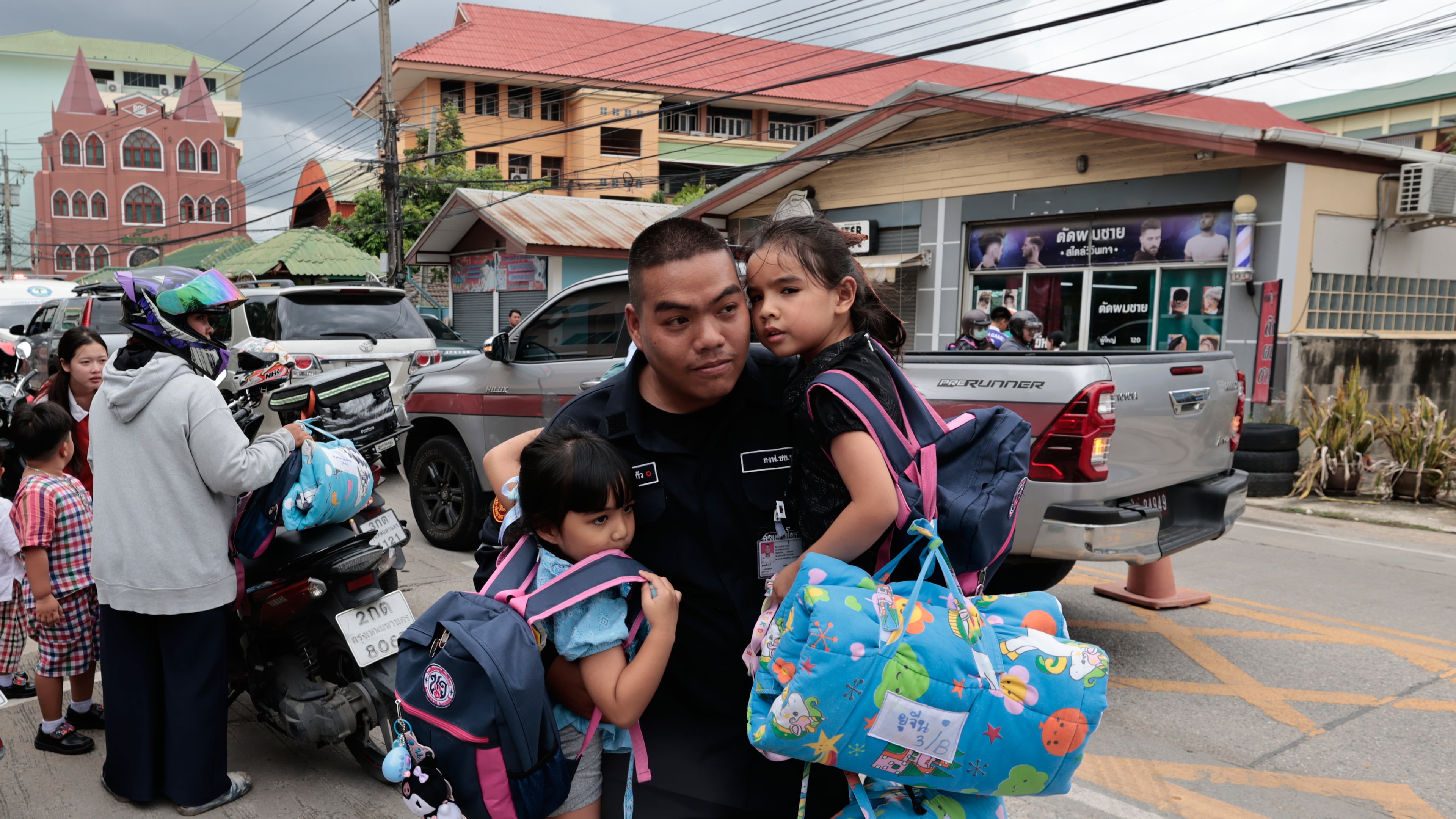 A man carries schoolgirls outside the site of a school shooting in Thailand's Nonthaburi province, Friday, Aug. 7, 2026. (AP Photo/Wason Wanichakorn)