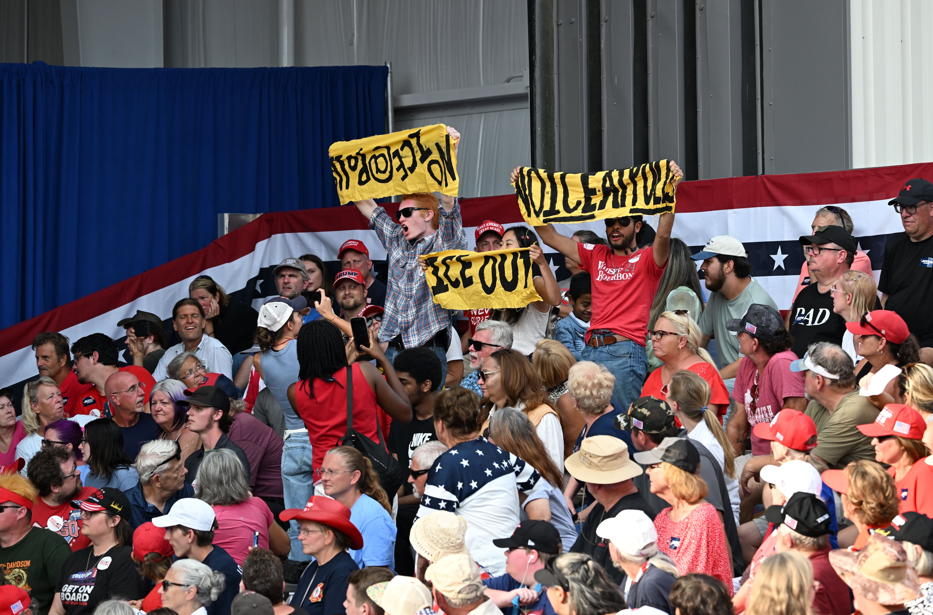 Protesters hold signs and chant as President Donald Trump speaks during a campaign rally at Dalton Municipal Airport on Friday, Oct. 16, 2026, in Dalton. (Hyosub Shin/AJC)