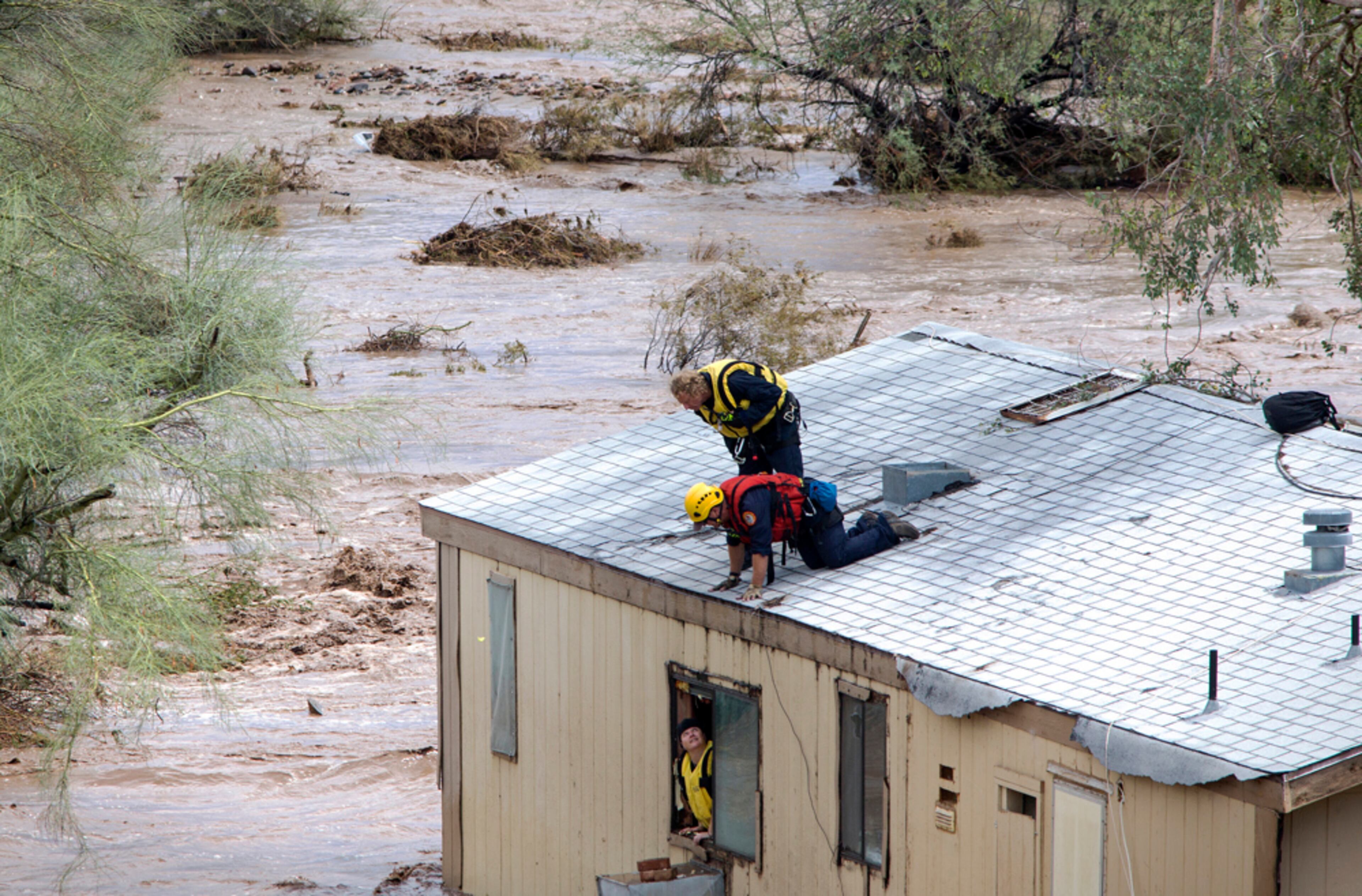 ROOF RESCUE--Firefighters talk with Tracey Tumlinson before she was rescued, Tuesday, Aug. 19, 2014, from her home flooded by the New River Wash, in New River, Arizona. (AP Photo/The Arizona Republic, Mark Henle)