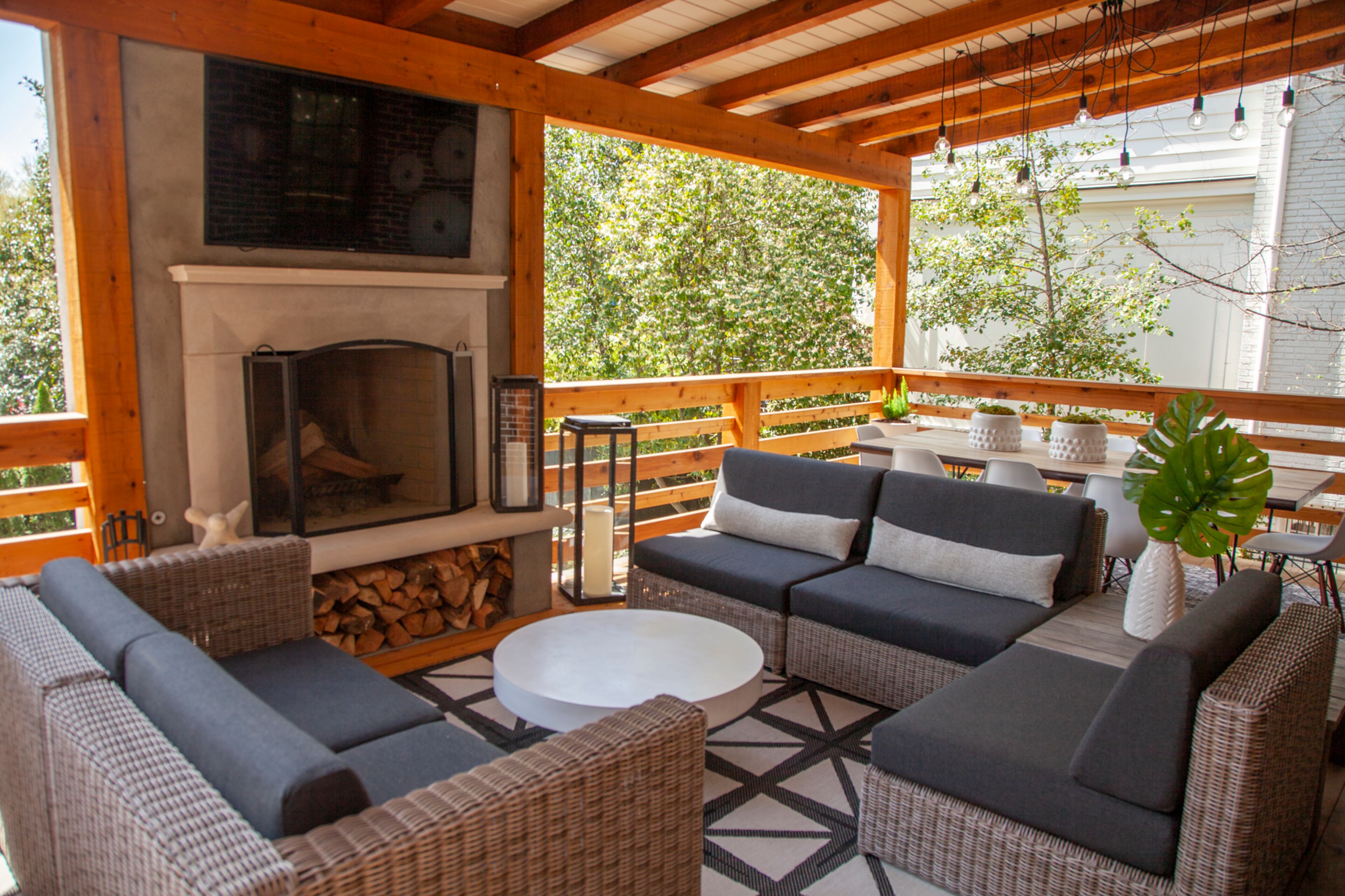 A cedar deck with a fireplace was added during 2017 renovations. In the covered area, the sectional is from Authenteak with Sunbrella cushions. A cement coffee table from CB2 is on a rug from Ballard Designs. The lanterns are from RH.